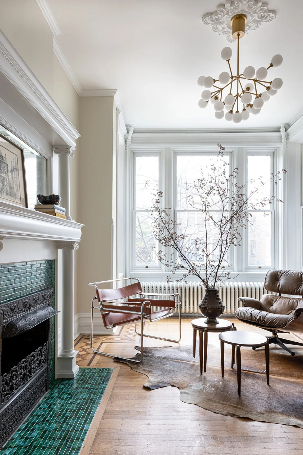 sitting room with green tiled fireplace and modern arm chairs sitting on a bear skin rug.