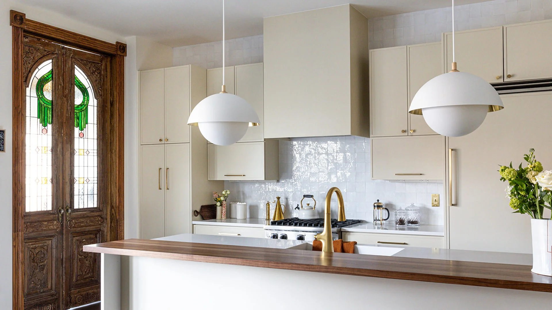modern creamy kitchen with antique wood doors with stained glass windows.