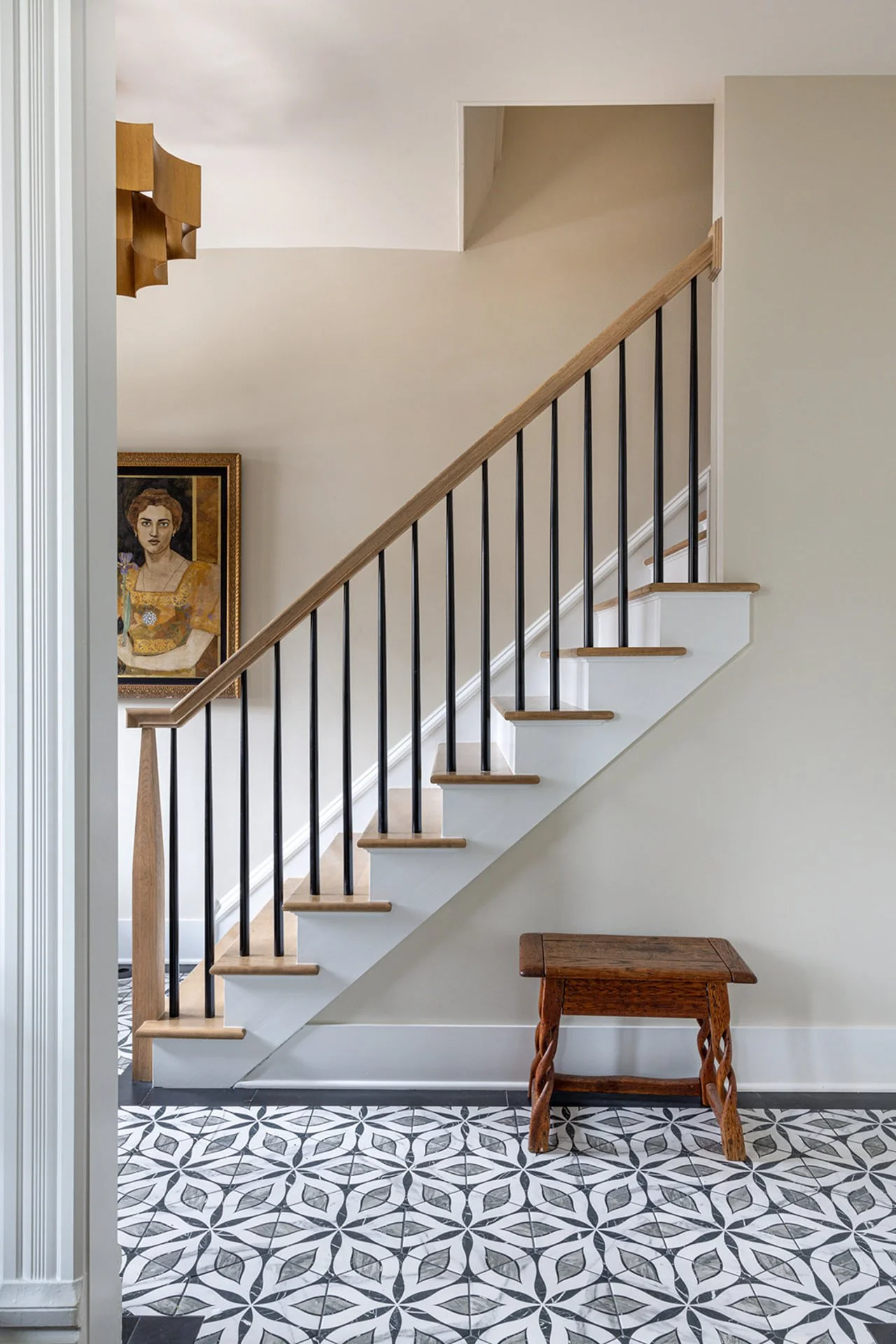 Minimal staircase with wood treads, black iron balusters, patterned tile floor, and neutral wall