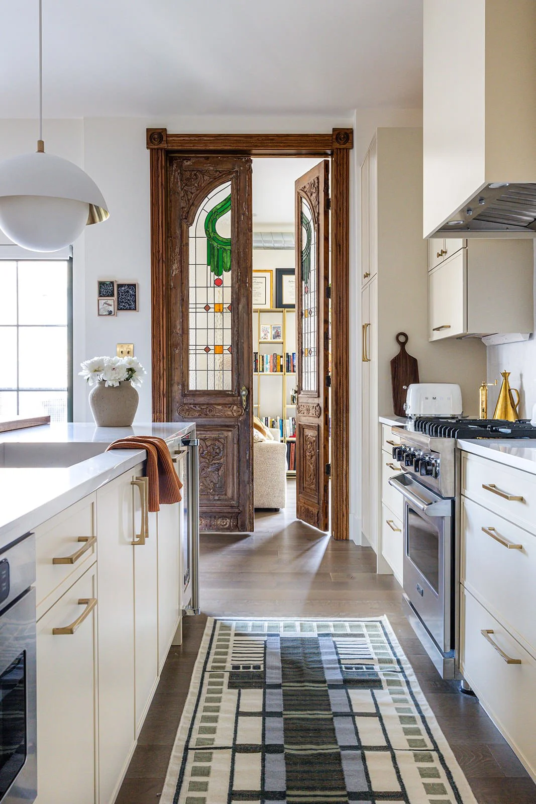 warm and inviting kitchen space with colorful runner, white cabinets and wood door accent