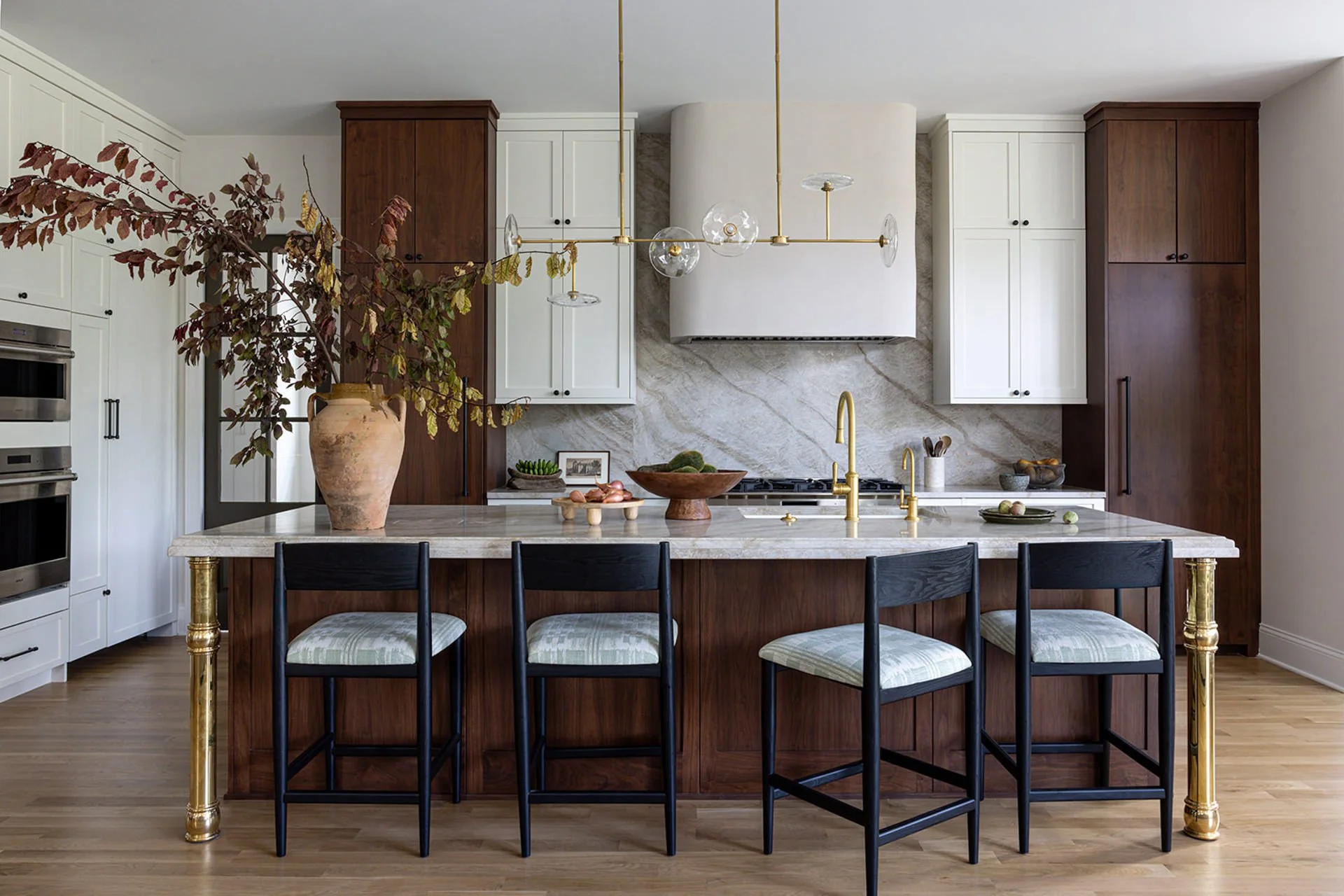walnut kitchen island with marble backsplash and white upper cabinets.