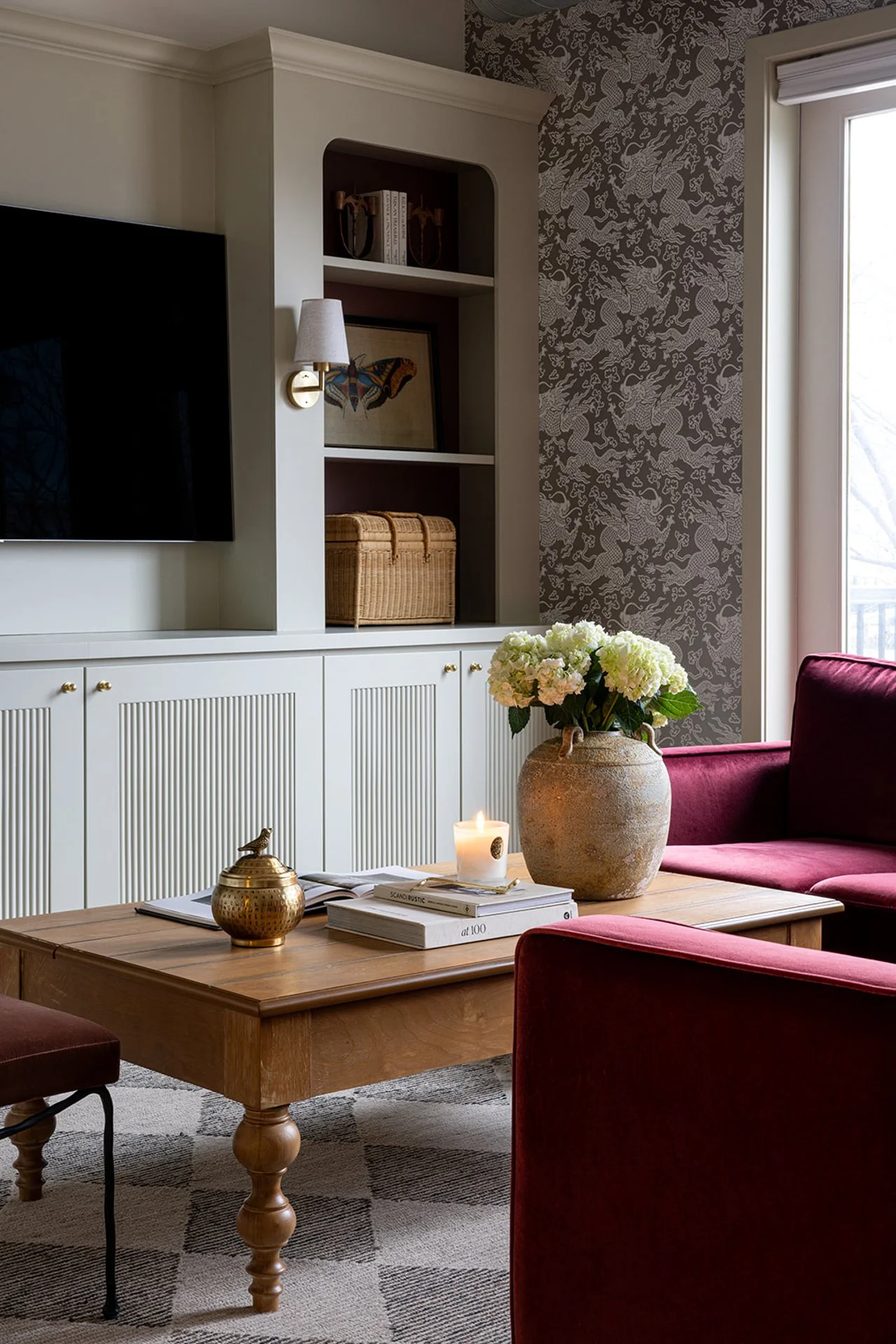 living space with dragon wallpaper and maroon velvet couch and checkered rug