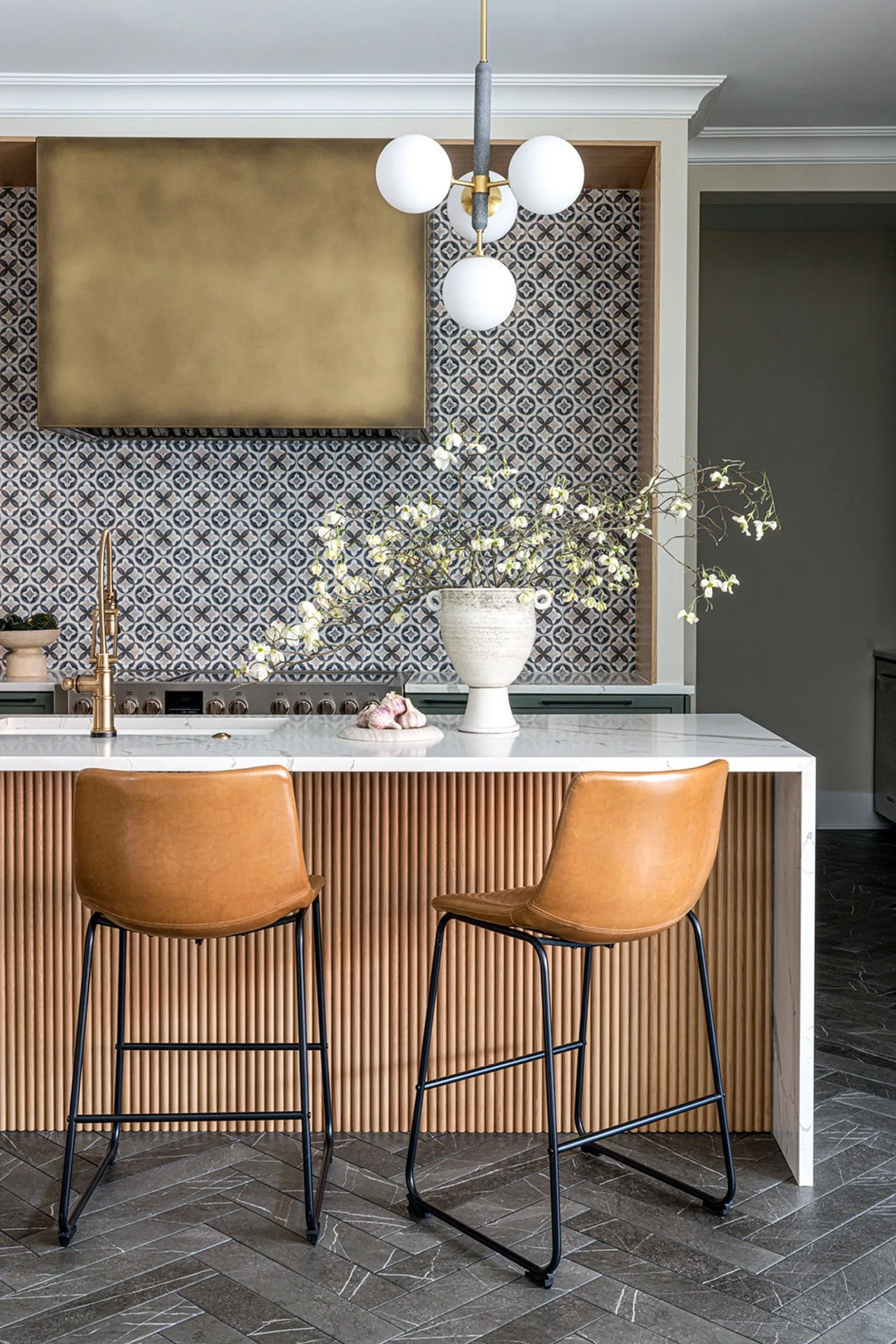 eclectic kitchen with wood slat island and moroccan tile backsplash with weathered brass range hood.