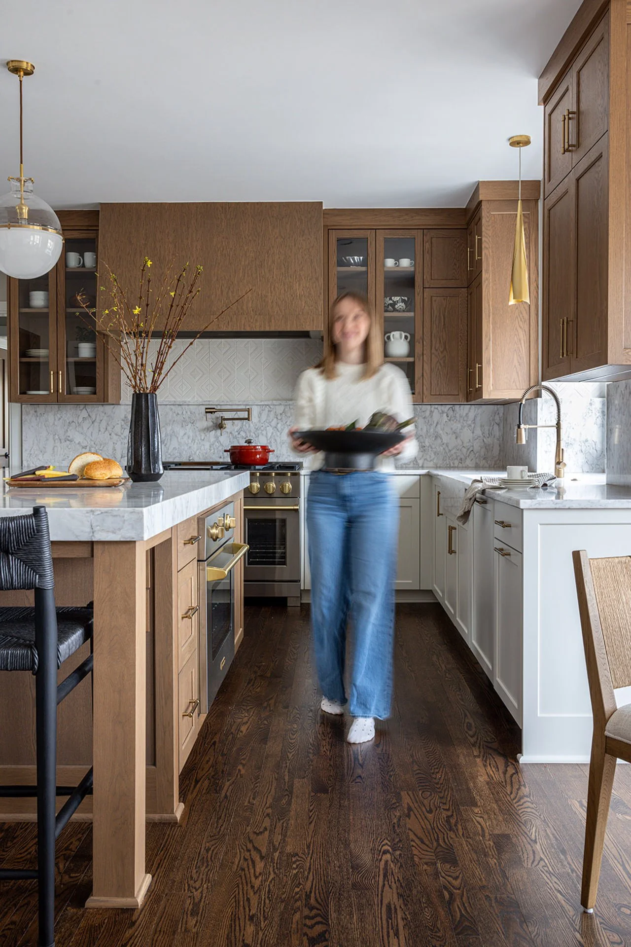 branding photo of designer walking through kitchen with light walnut cabinets