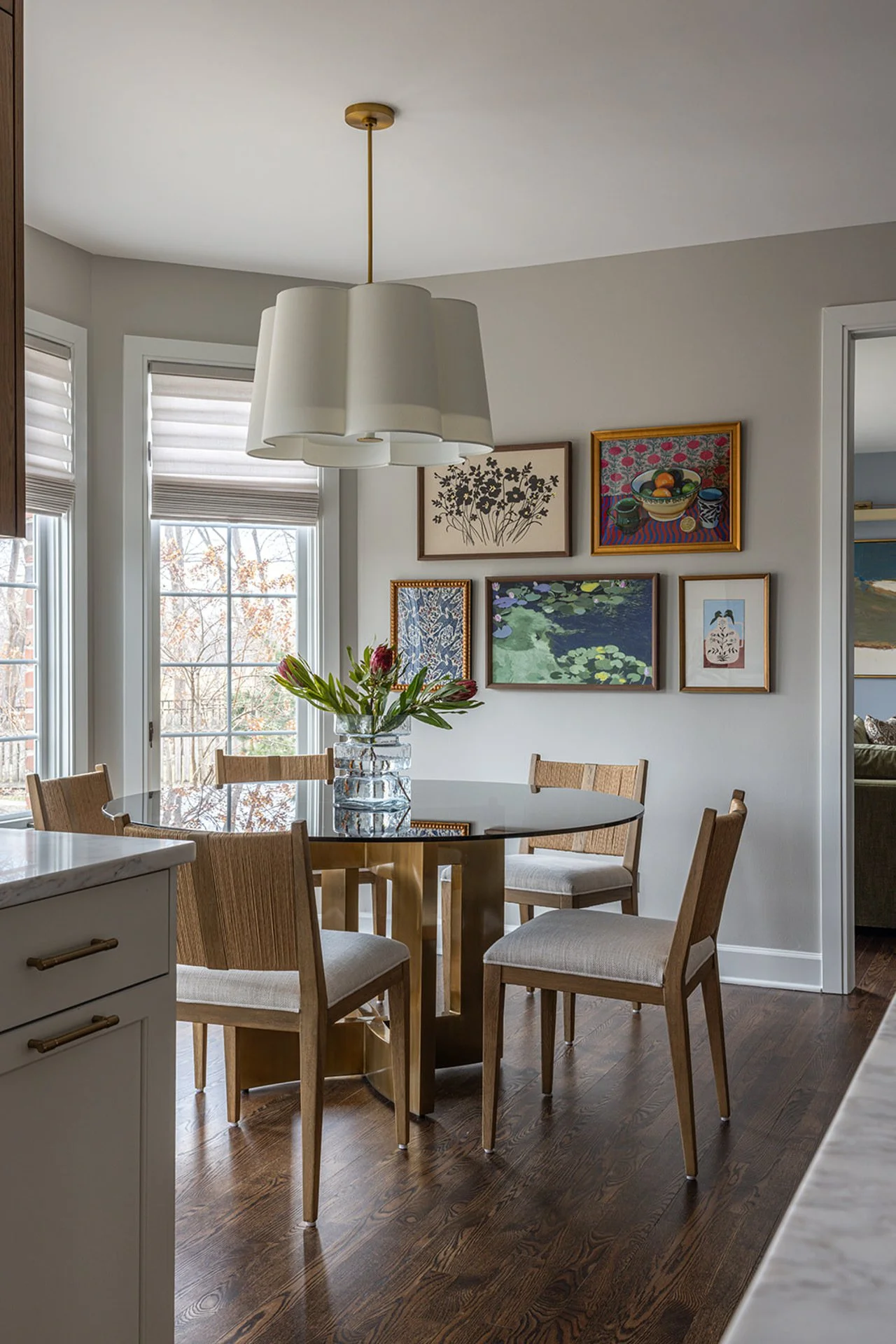 kitchen dinette with colorful art gallery wall and large white light fixture.