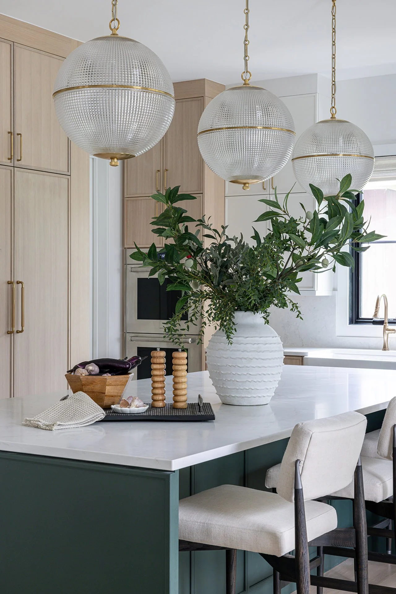 beautiful kitchen with green island and large glass pendant lights.