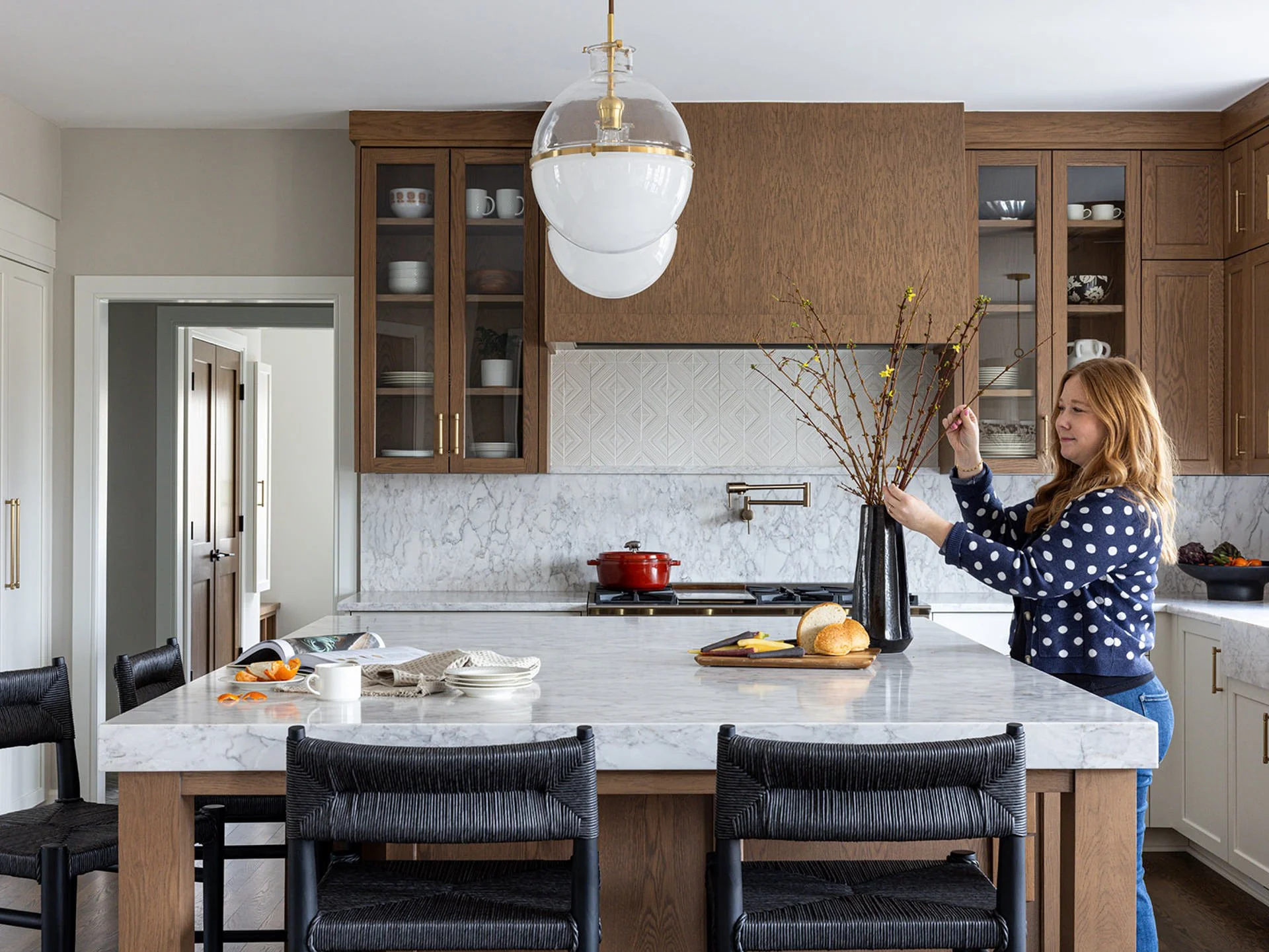 interior designer styling florals for a kitchen photoshoot with white oak uppers and marble countertop and backsplash.