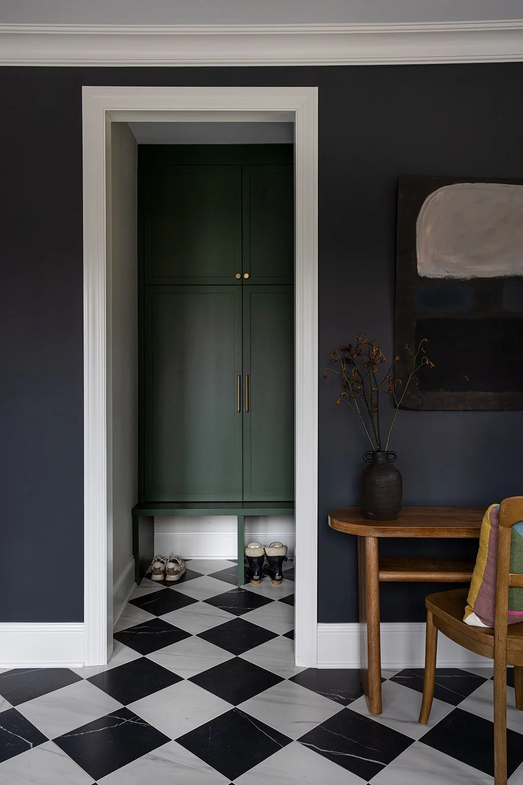 black and white marble tile floor with dark green mudroom built ins.