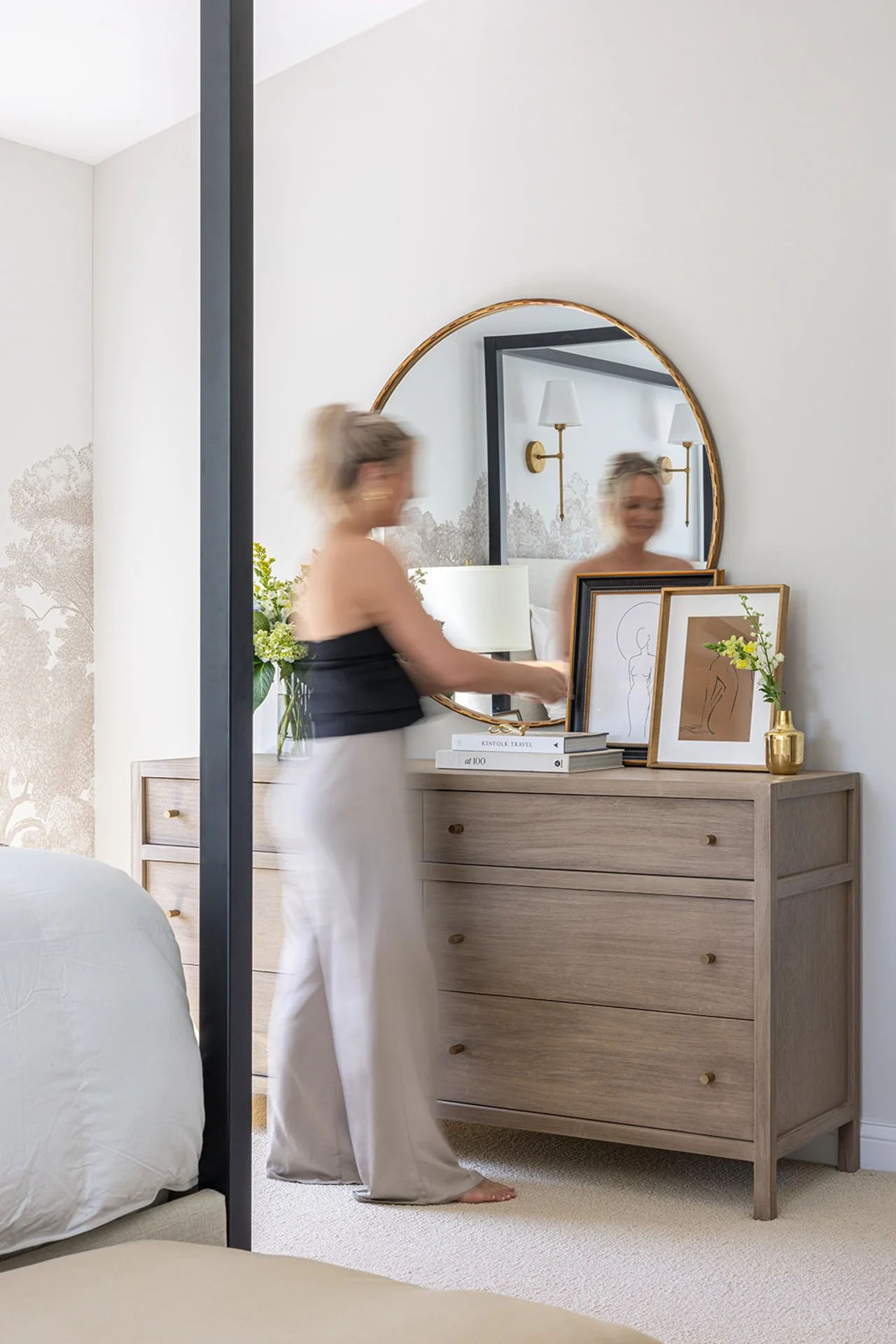 interior designer styling a bedroom dresser with fresh florals and books.