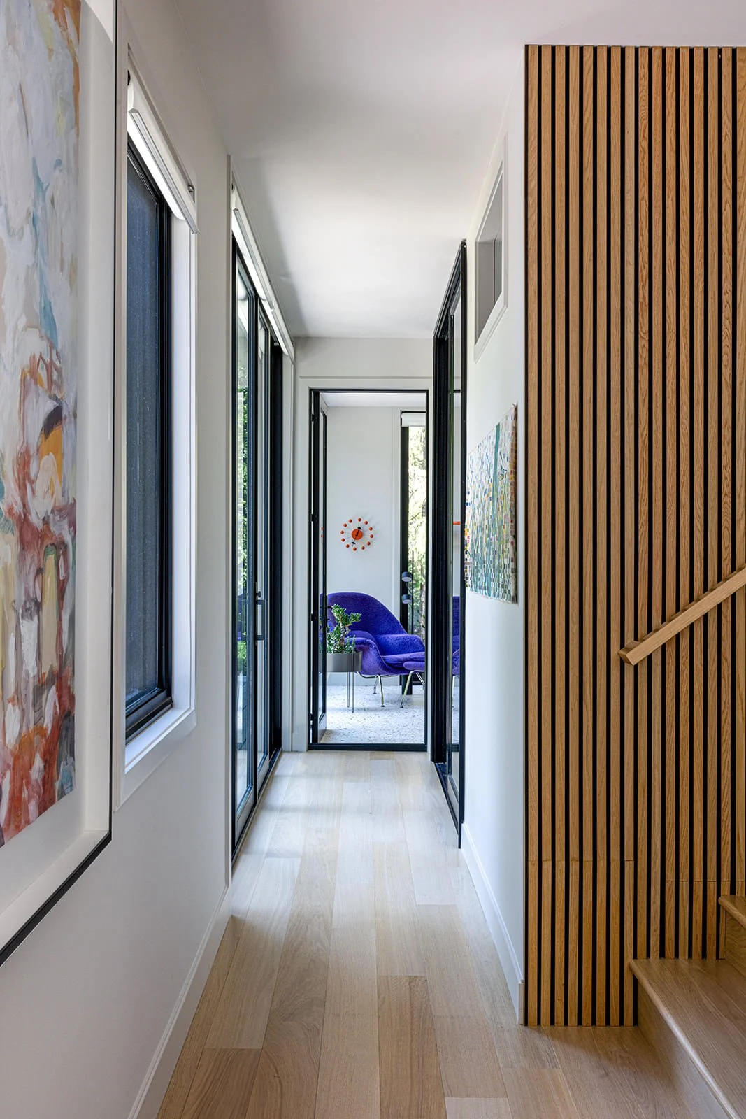 hallway with large artwork and fluted wood detail on wall