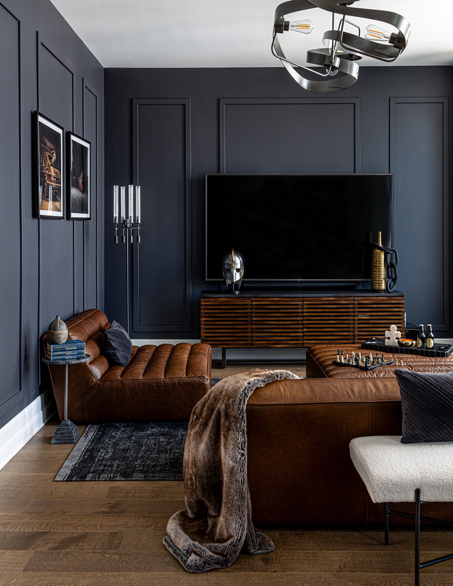 masculine living space with leather couches, dark walls, and fur throw blanket.
