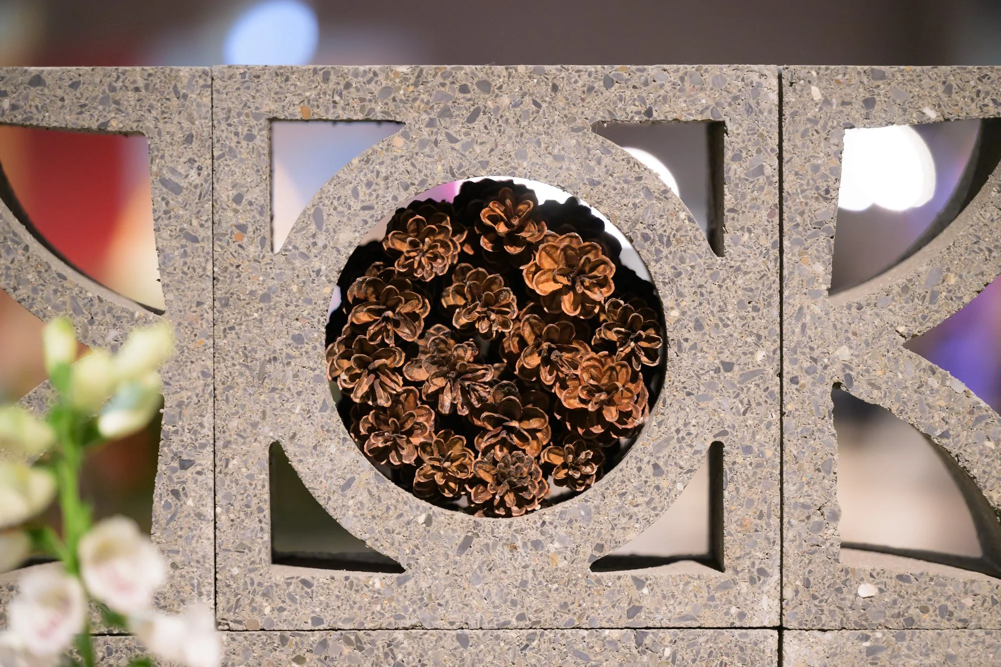 Decorative stone structure with circular cutouts, containing pinecones