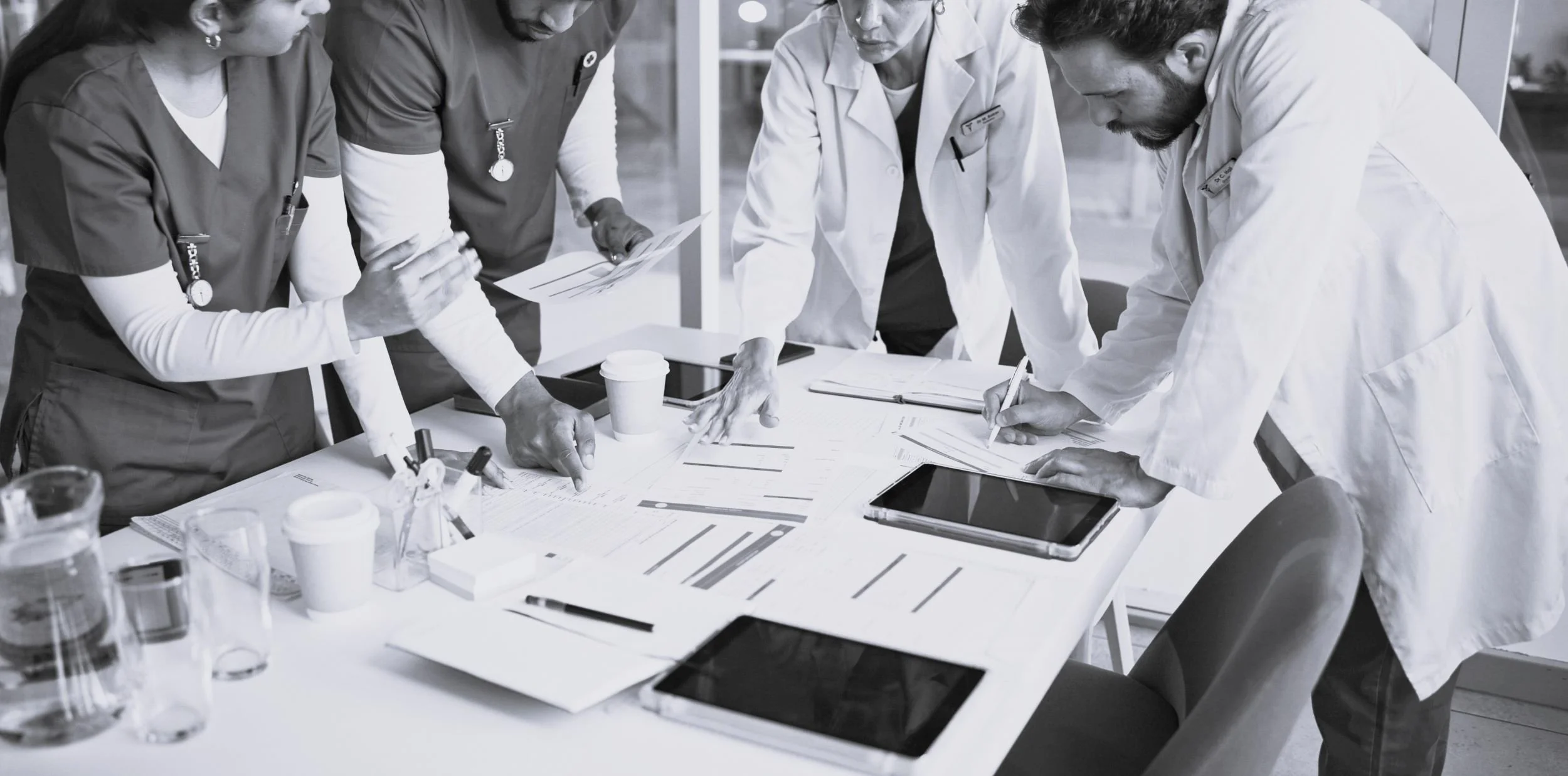 Group of healthcare professionals in a meeting room reviewing charts and documents.