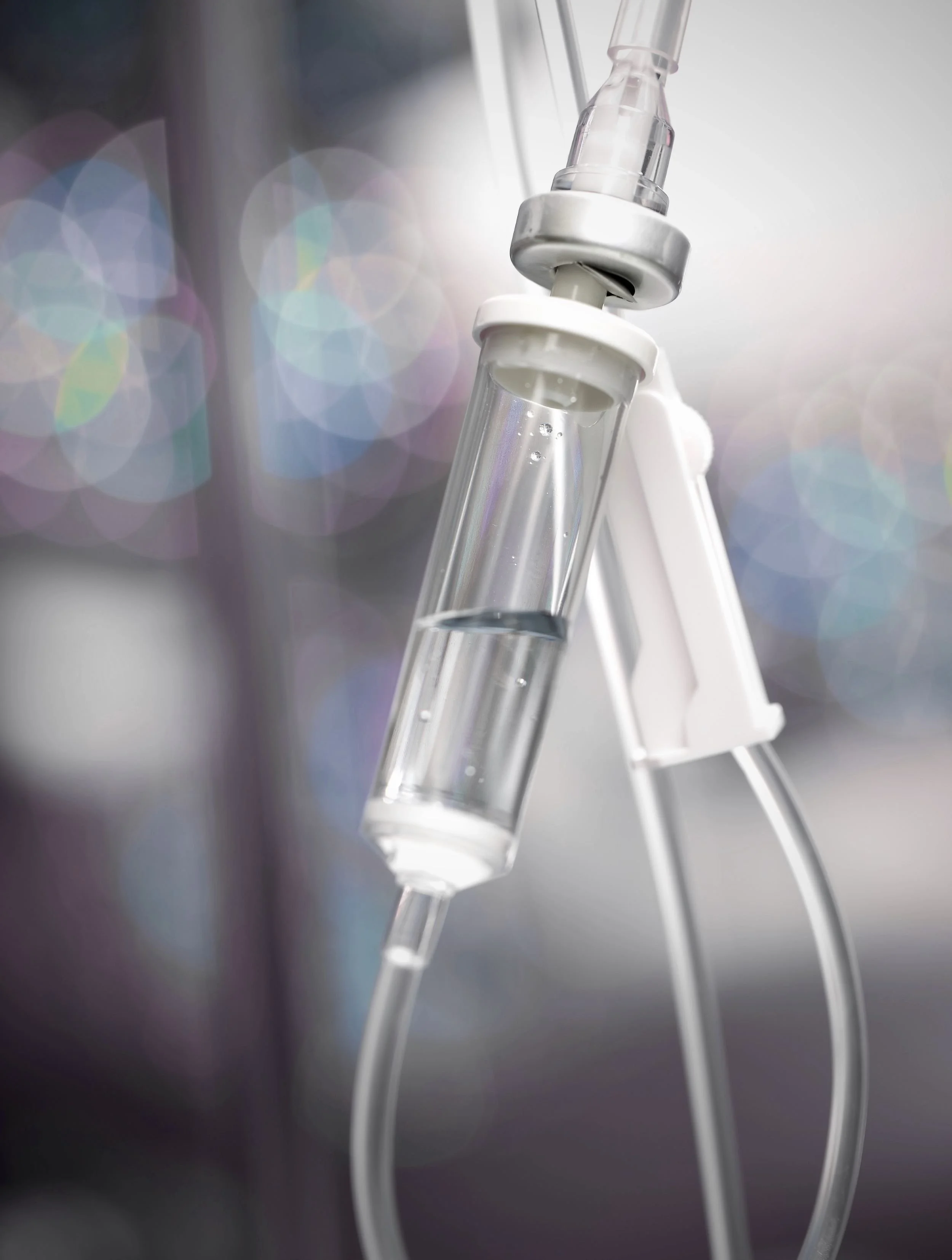 A medical IV drip hanging with tubing, ready to administer fluids or medication to a patient.