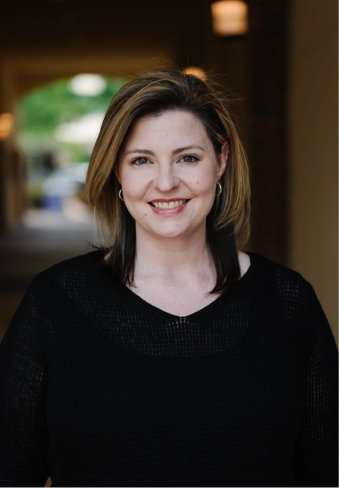 Stephanie Vance, Licensed Professional Counselor in Flowood, MS, with shoulder-length brown hair, wearing a black top, smiling, with blurred indoor background.