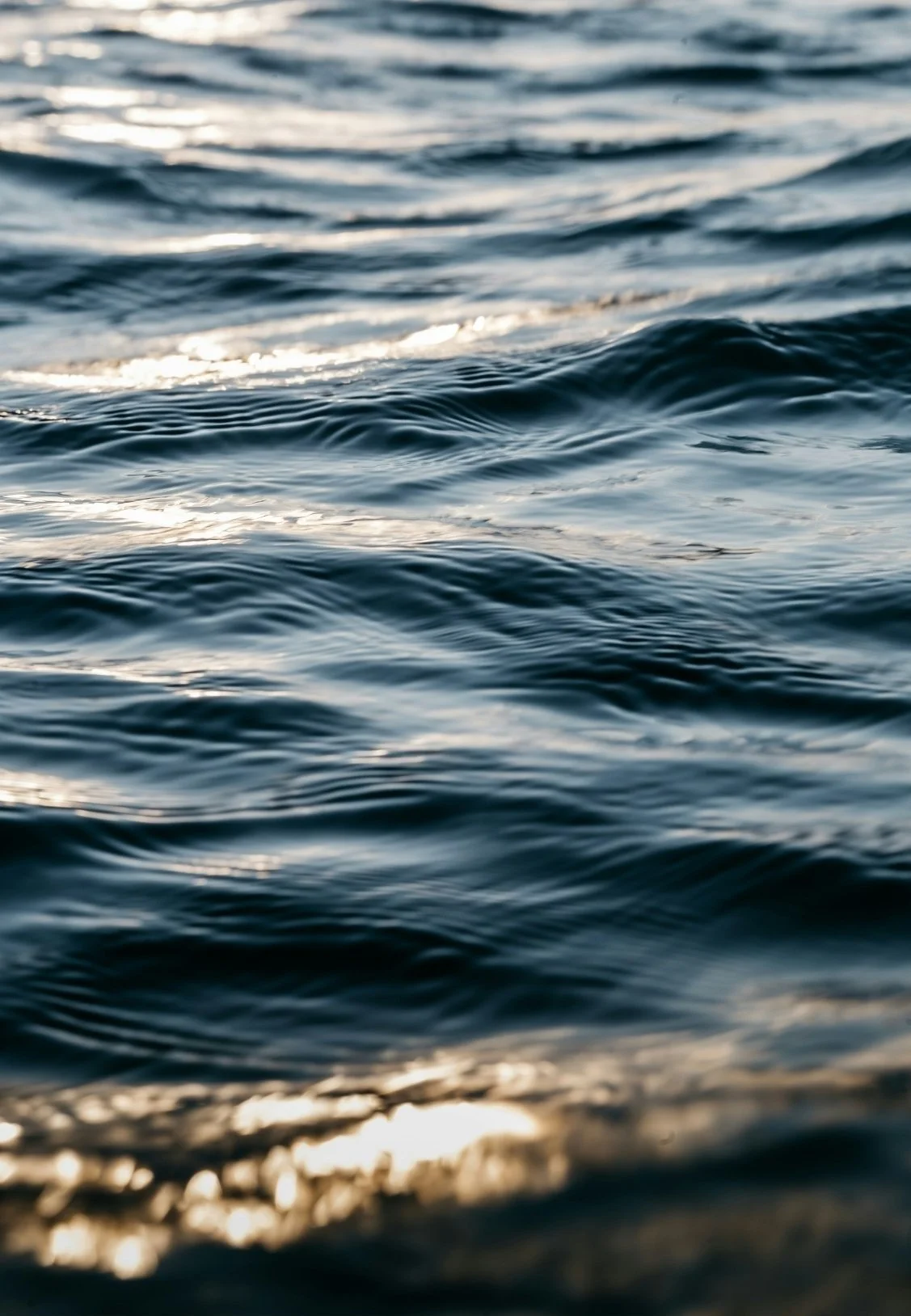 Close-up view of gentle ocean waves reflecting sunlight.