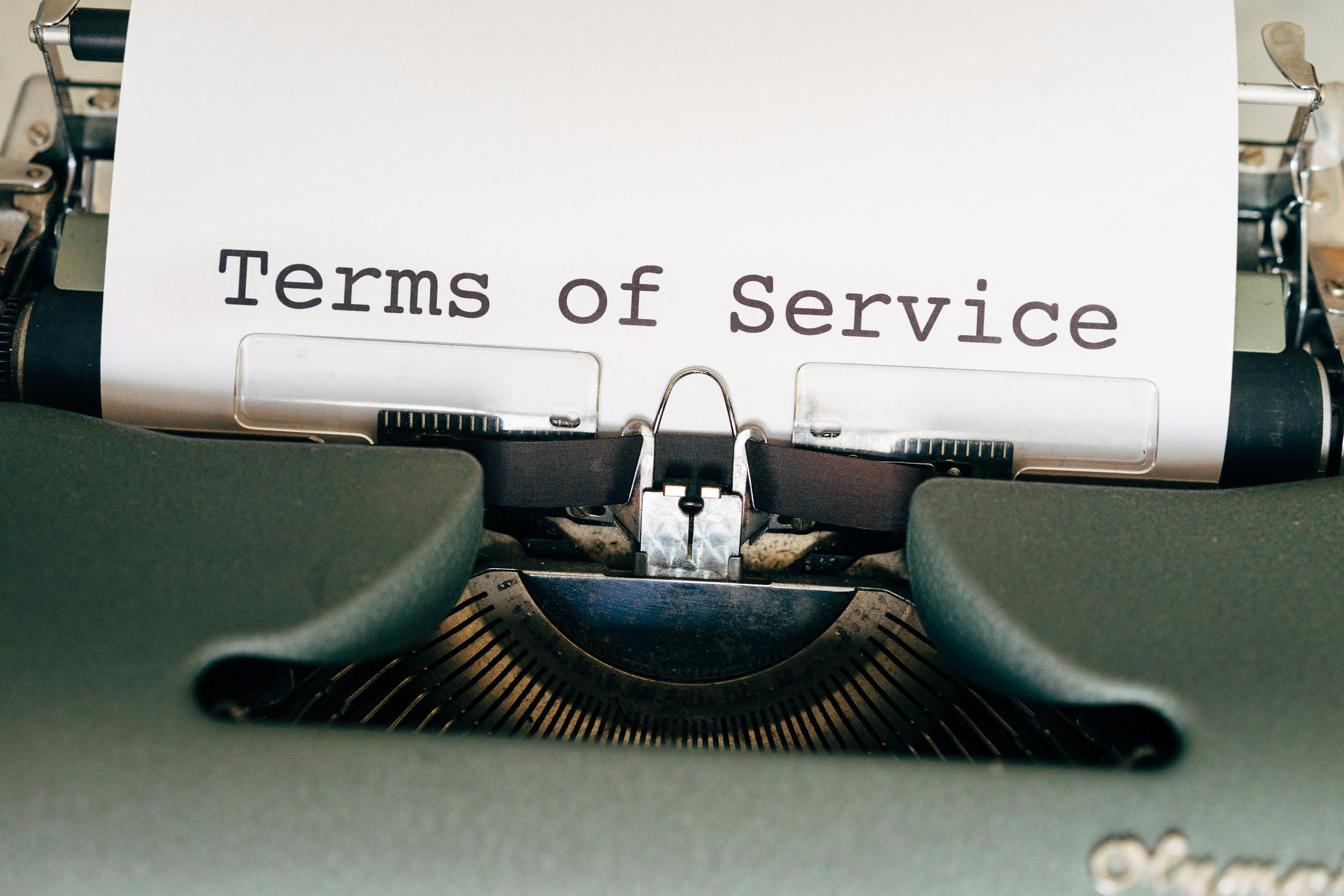 Close-up of a typewriter with a white sheet of paper that reads 'Terms of Service' in brown text.