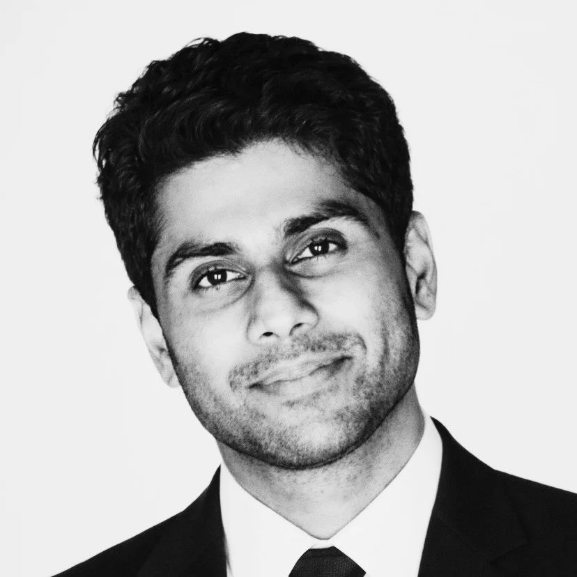 Black and white portrait of Bipin Suresh - CEO of In Ear Voice - in a suit with a slight smile.