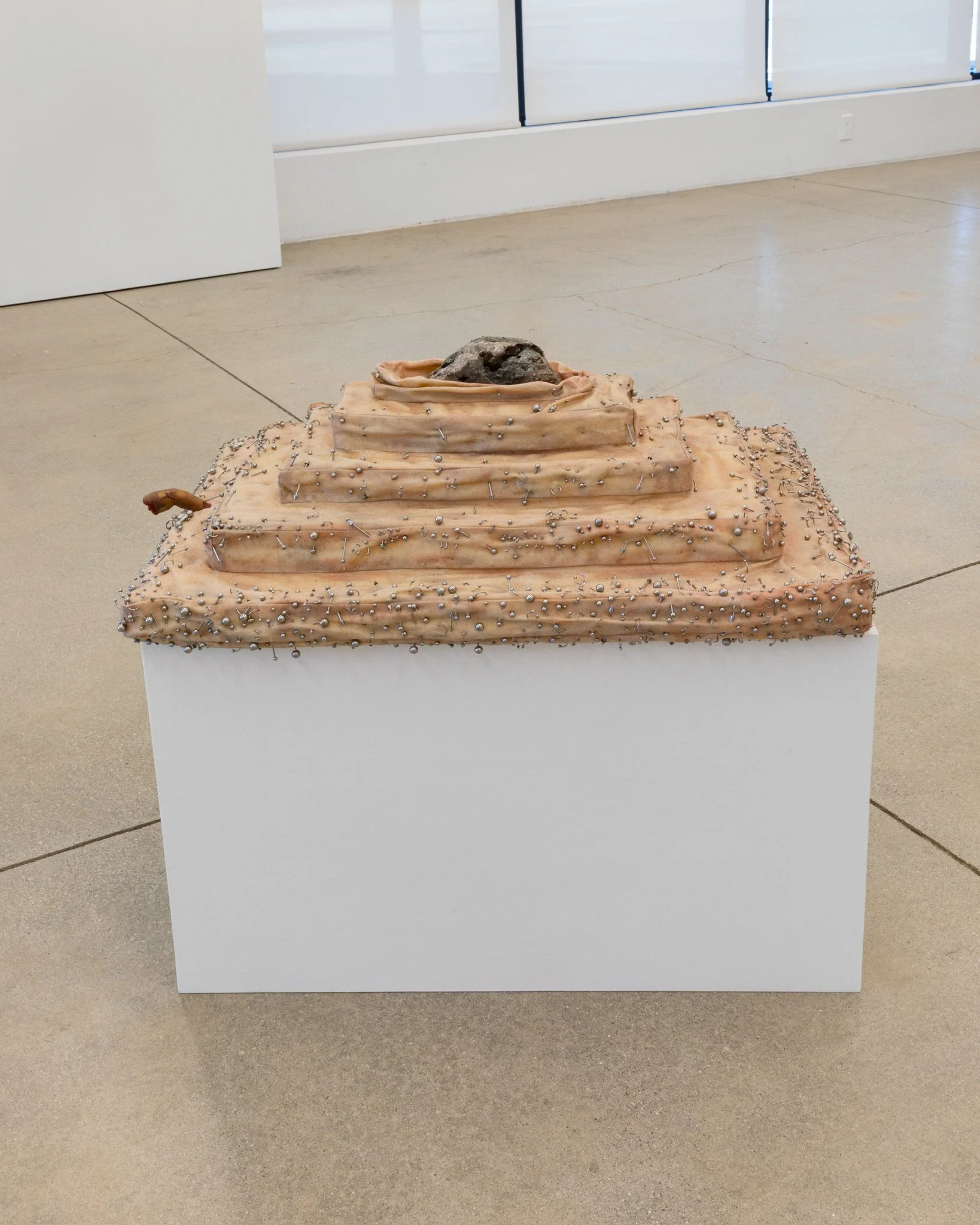 "Cunt Rock It Till You Try It (Metamorphic)".
Beeswax, fabric, foam, encaustic pigment, piercings, rock. 8” H X 19.5” W X 26.5” D
2026.