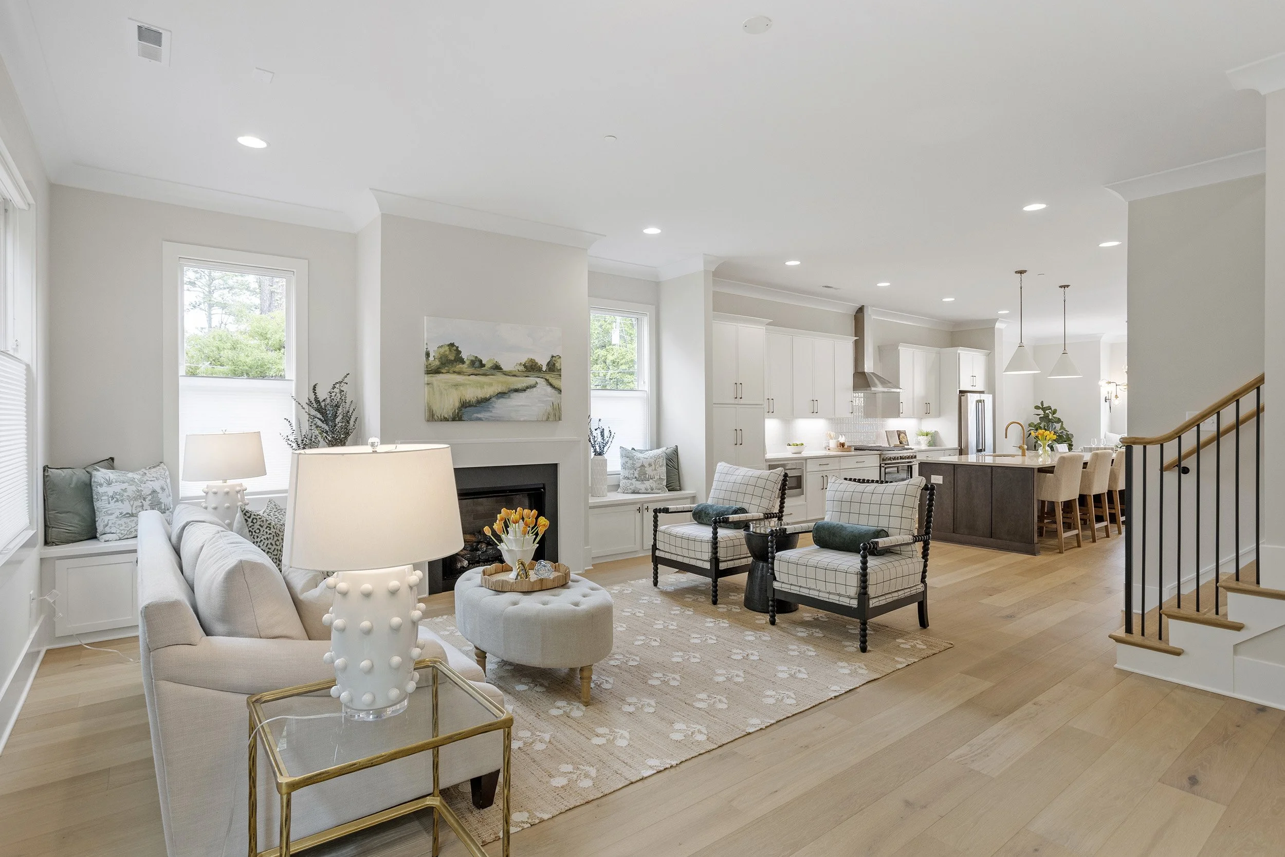 Open-concept living room and kitchen with white and neutral tones, hardwood floors, and modern decor.