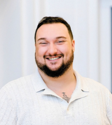 Smiling bearded man in a white collared shirt posing for a portrait