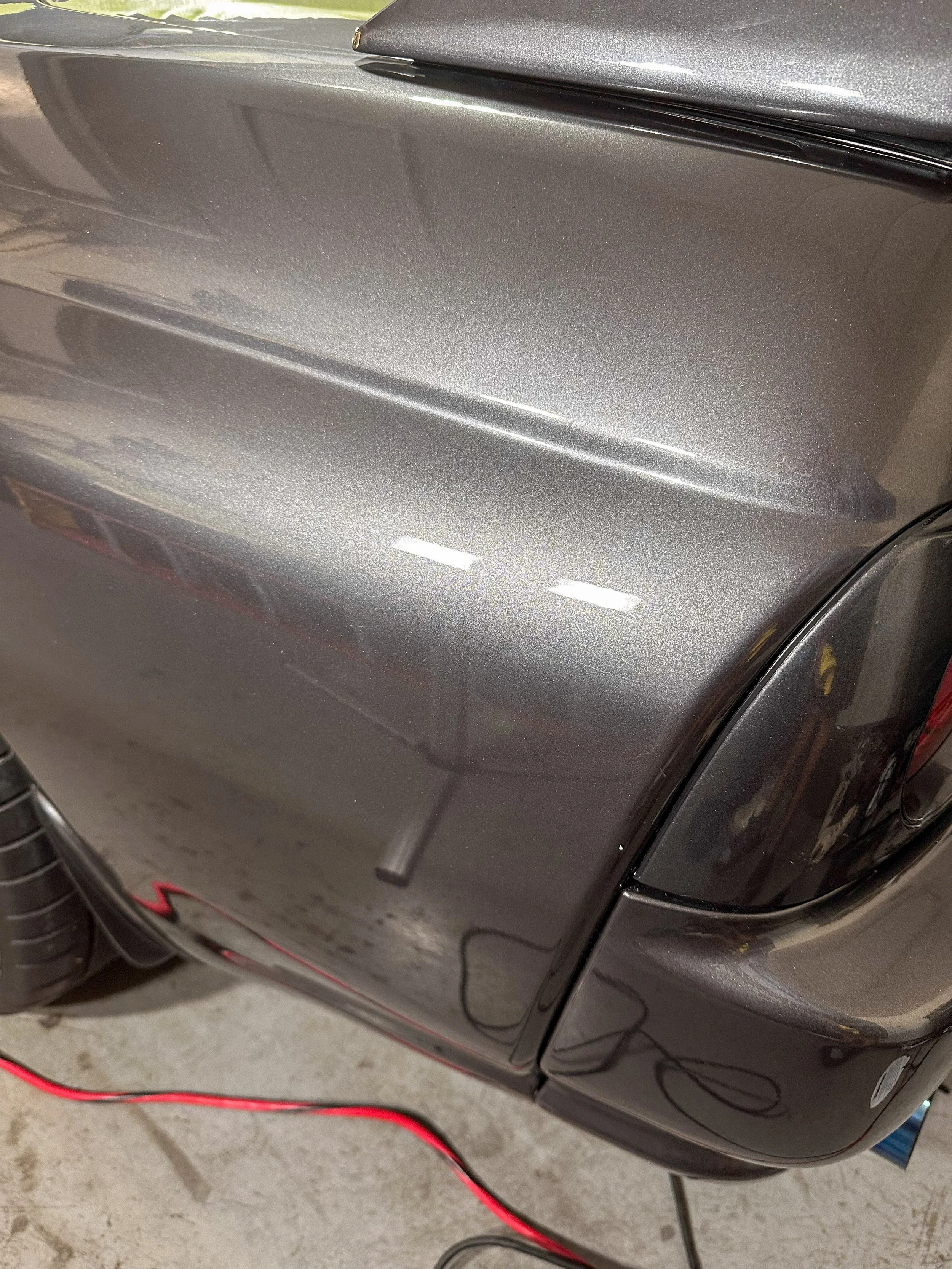 Close-up of a metallic gray car door with some reflections and a black handle.