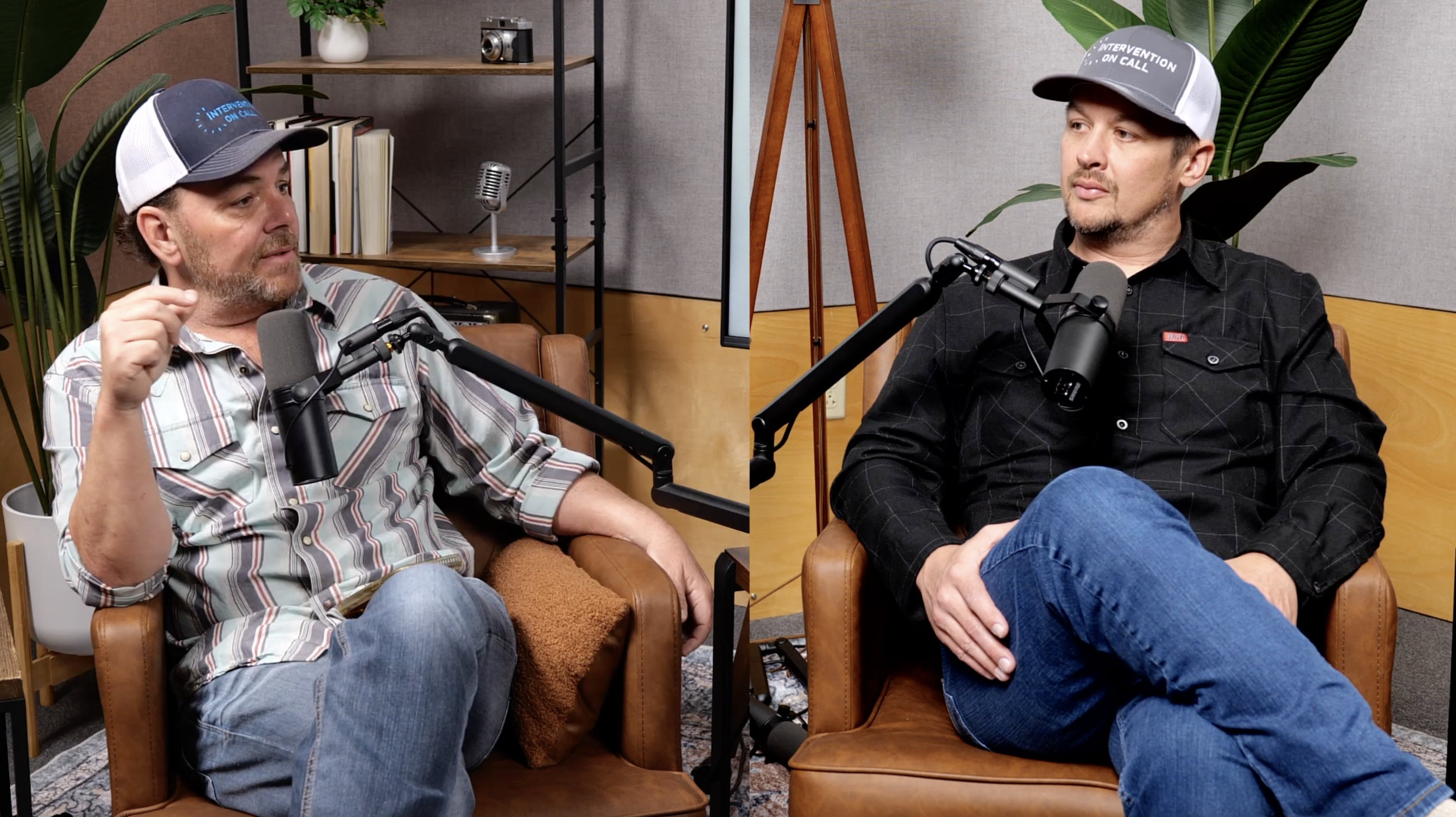 Two men sitting in chairs having a conversation during a podcast or interview. Both are wearing baseball caps and speaking into microphones. The background has shelves with books and decorative items, and there are large green plants near them.
