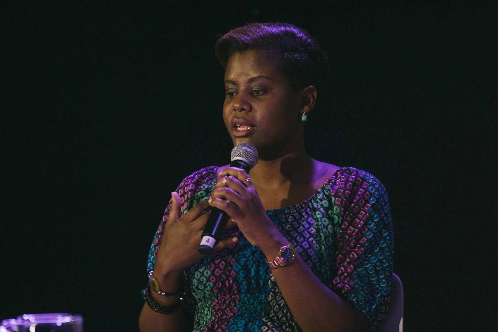 Consolee Nishimwe, survivor of the 1994 Genocide Against the Tutsi, shares her testimony on stage with a microphone.
