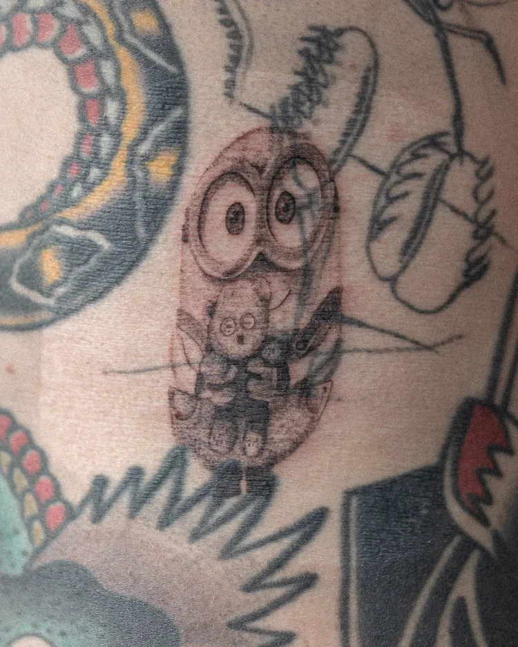 Tatouage d'un personnage de dessin animé avec de grands yeux, sur la peau.