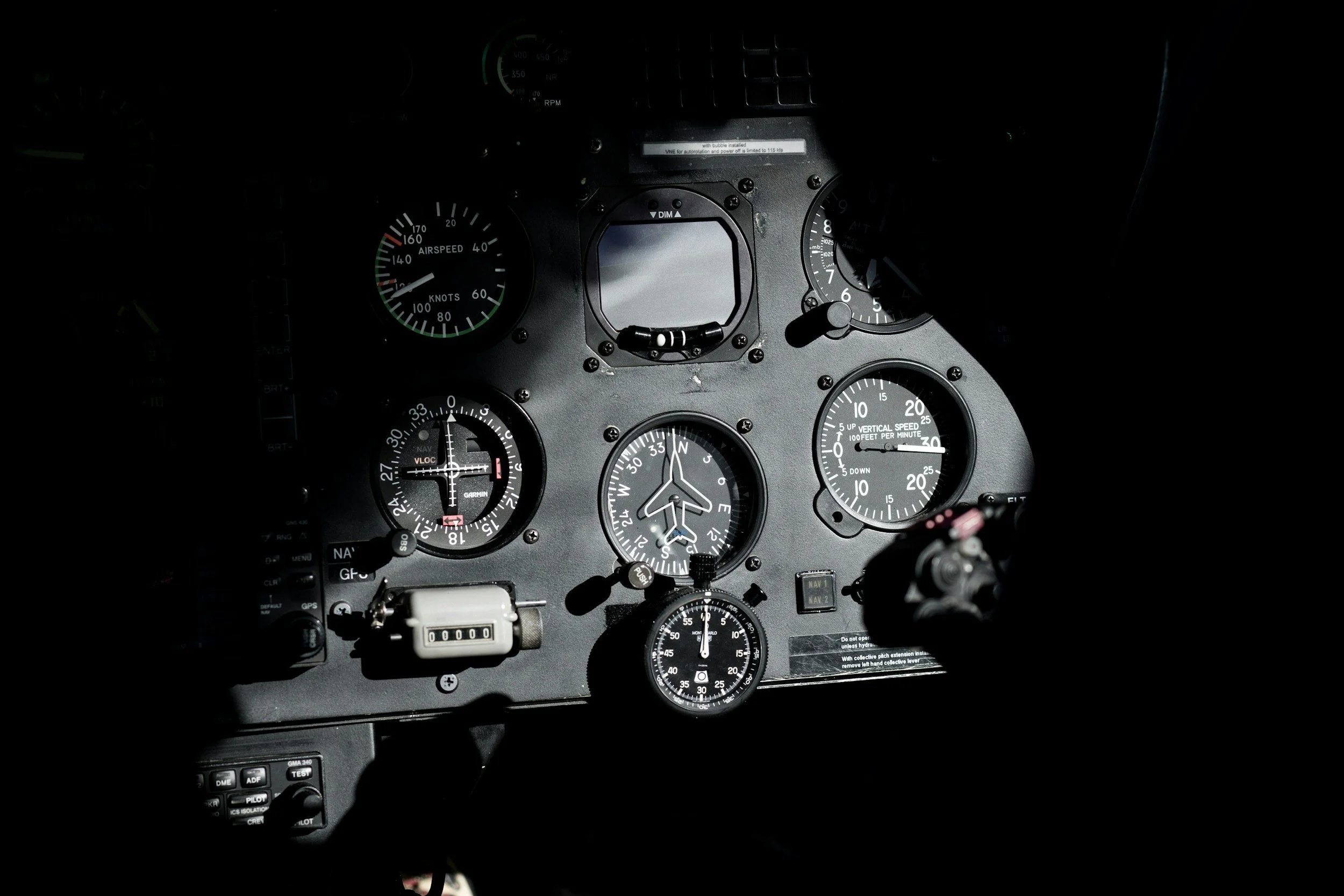 Cockpit of an aircraft with various gauges and controls, including airspeed, vertical speed, and altitude indicators, some partially visible in darkness.