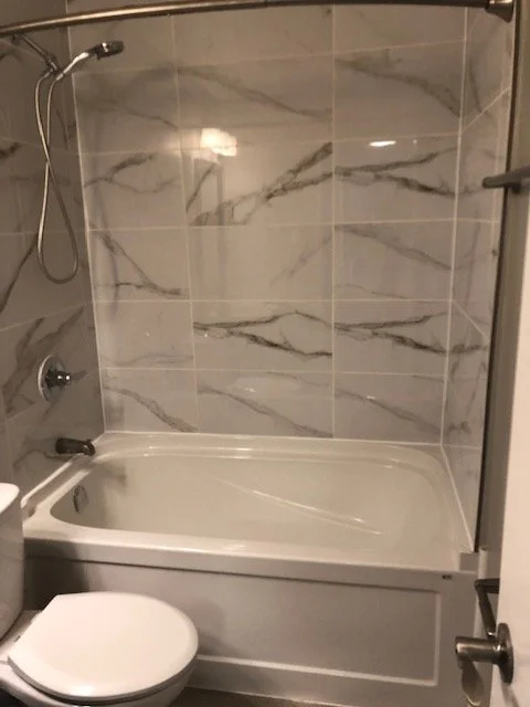 Bathroom with a bathtub, tiled walls, and a showerhead.