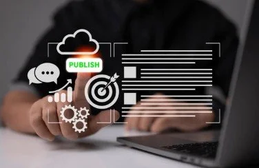 Person typing on a laptop with digital icons of a cloud, speech bubble, publish button, target, and gears overlayed.