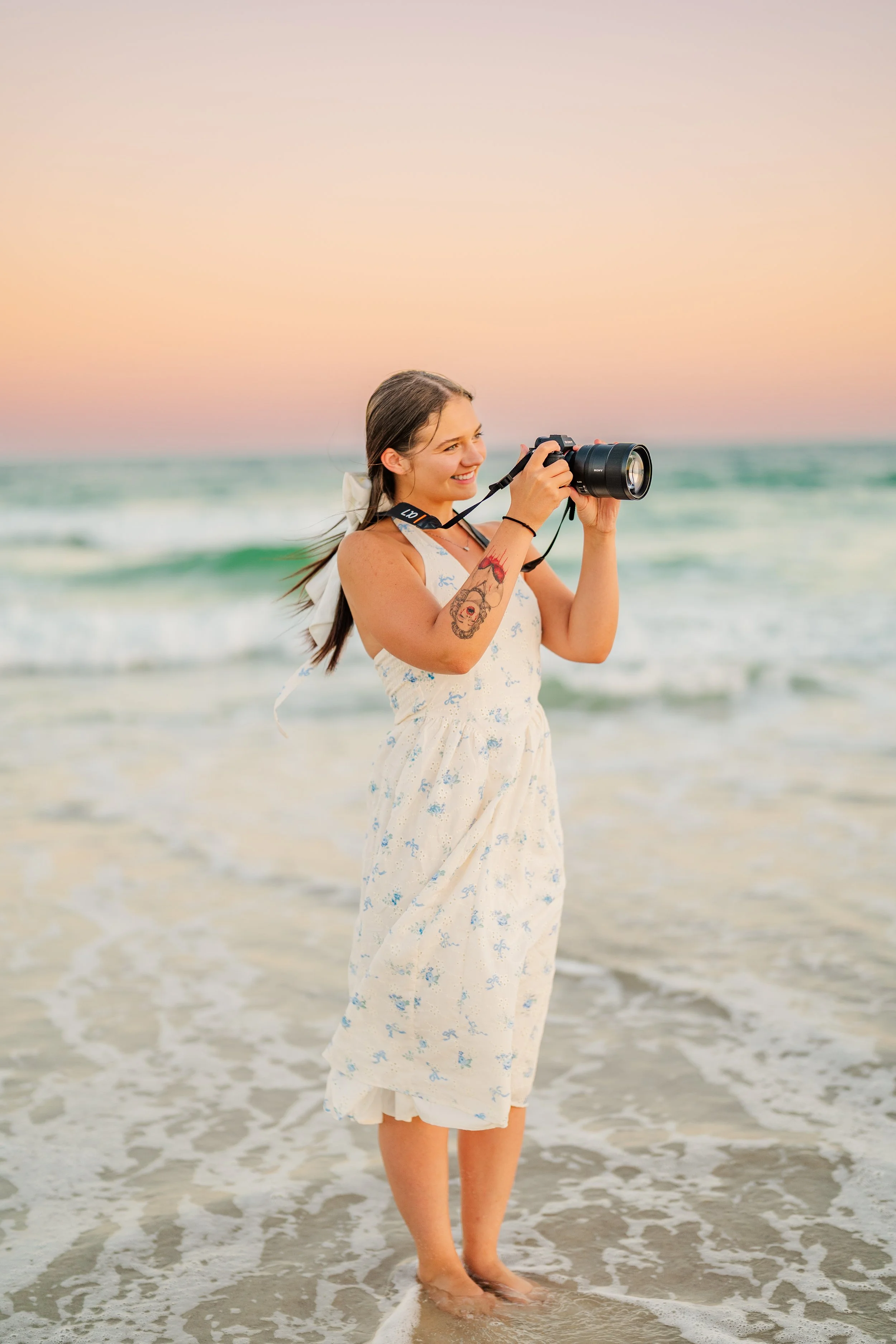 Mackenzie, Gulf Shores Alabama photographer, holding her camera on the beach ready for a sunset session
