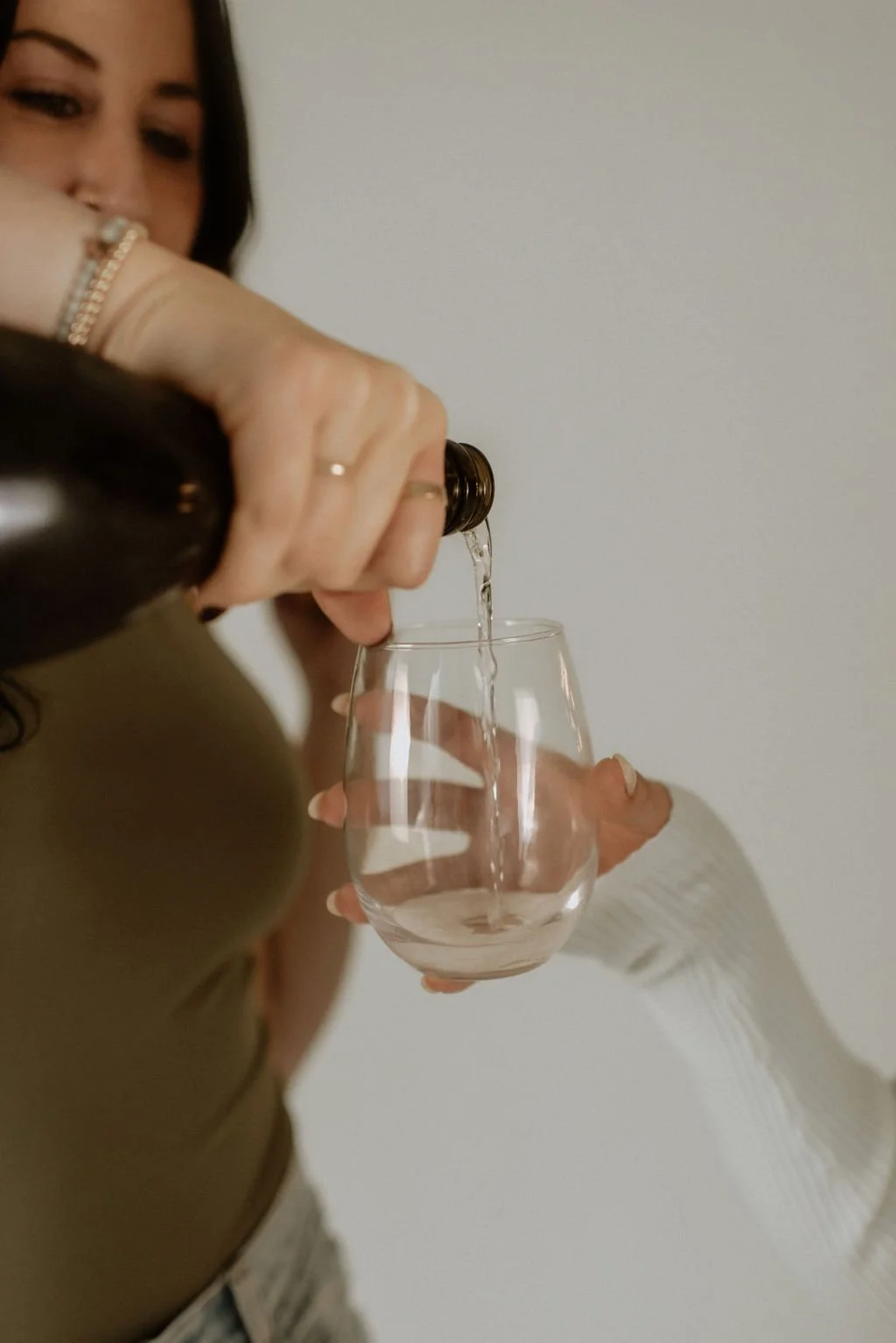 Person pouring clear liquid into a wine glass