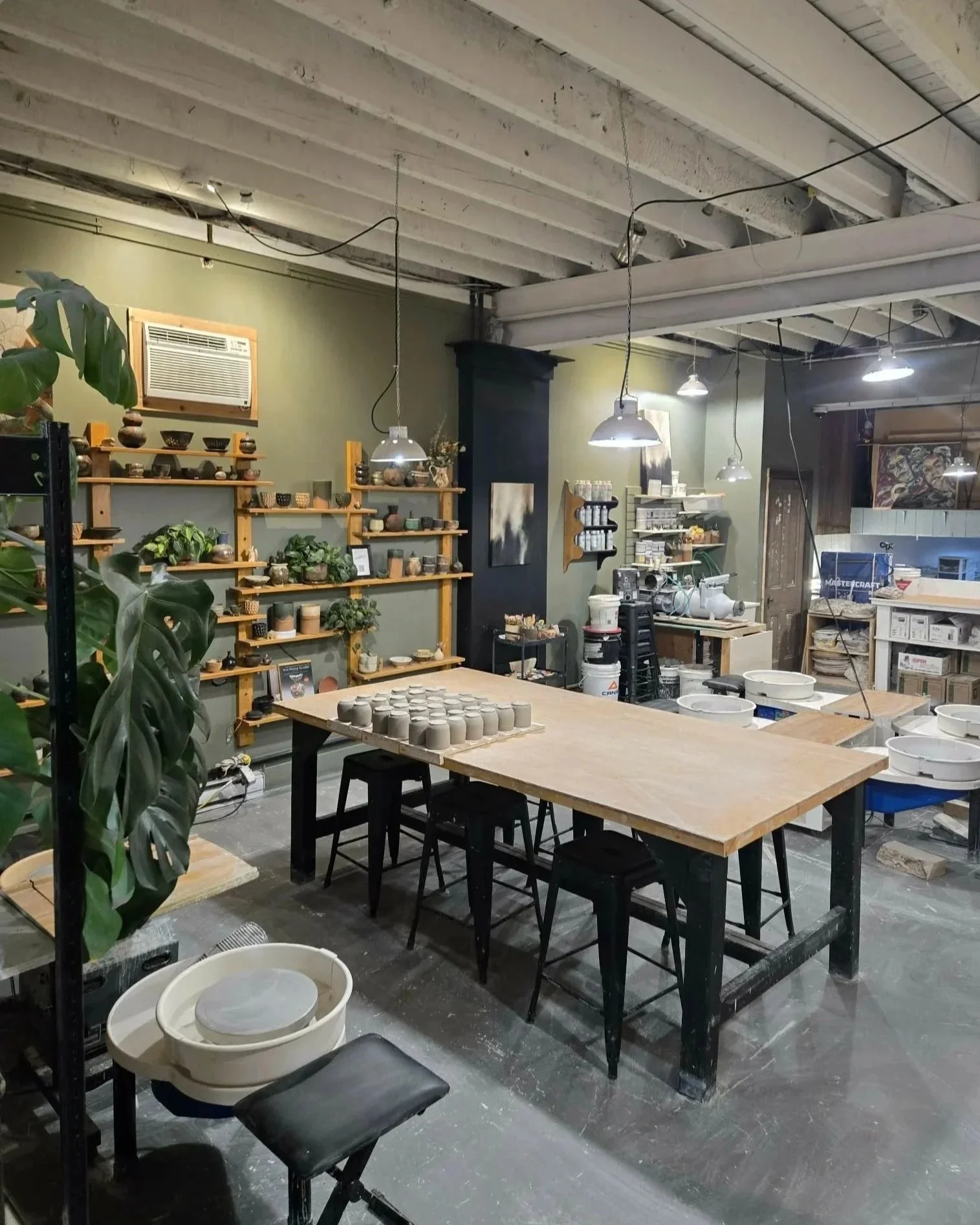 Atelier de poterie avec tables, étagères de céramiques, plantes et outils, ambiance d'atelier artistique