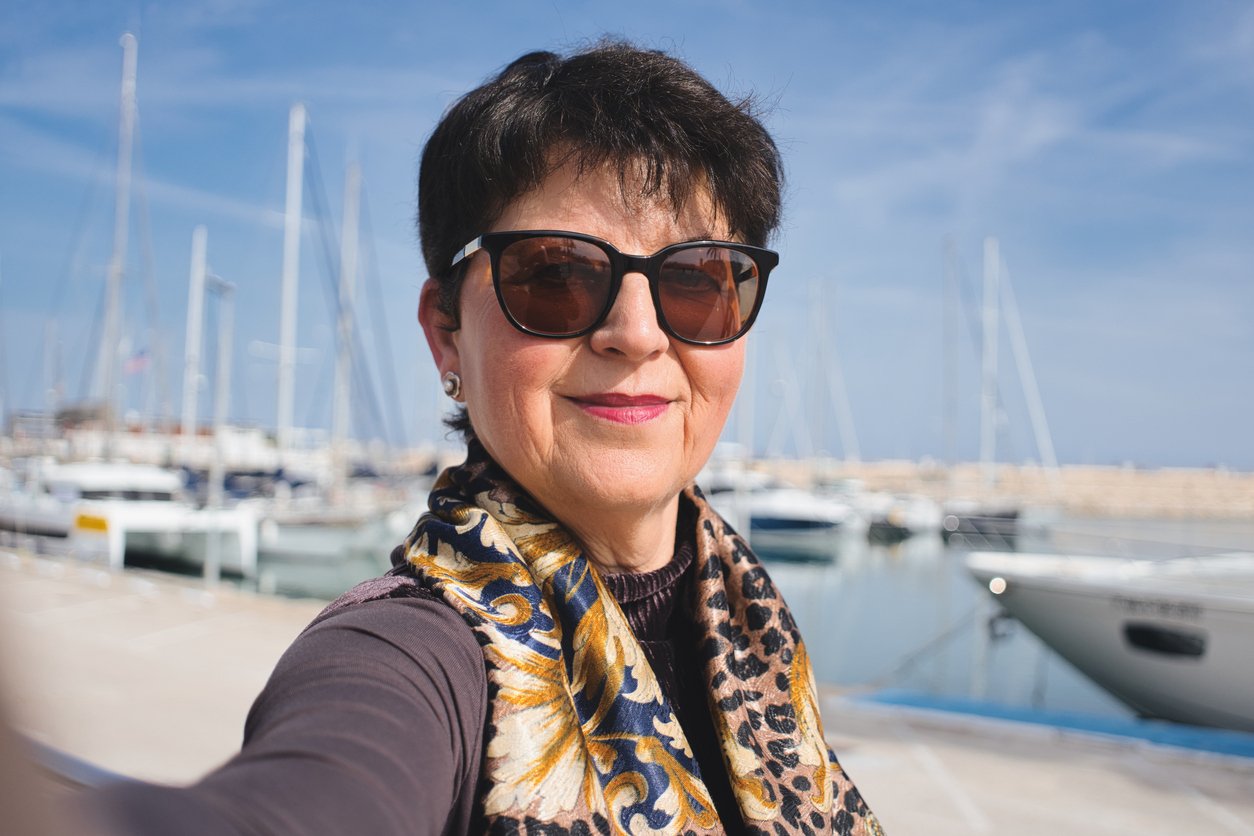 Portrait of an older woman wearing sunglasses and a patterned scarf, representing a health plan target user persona.