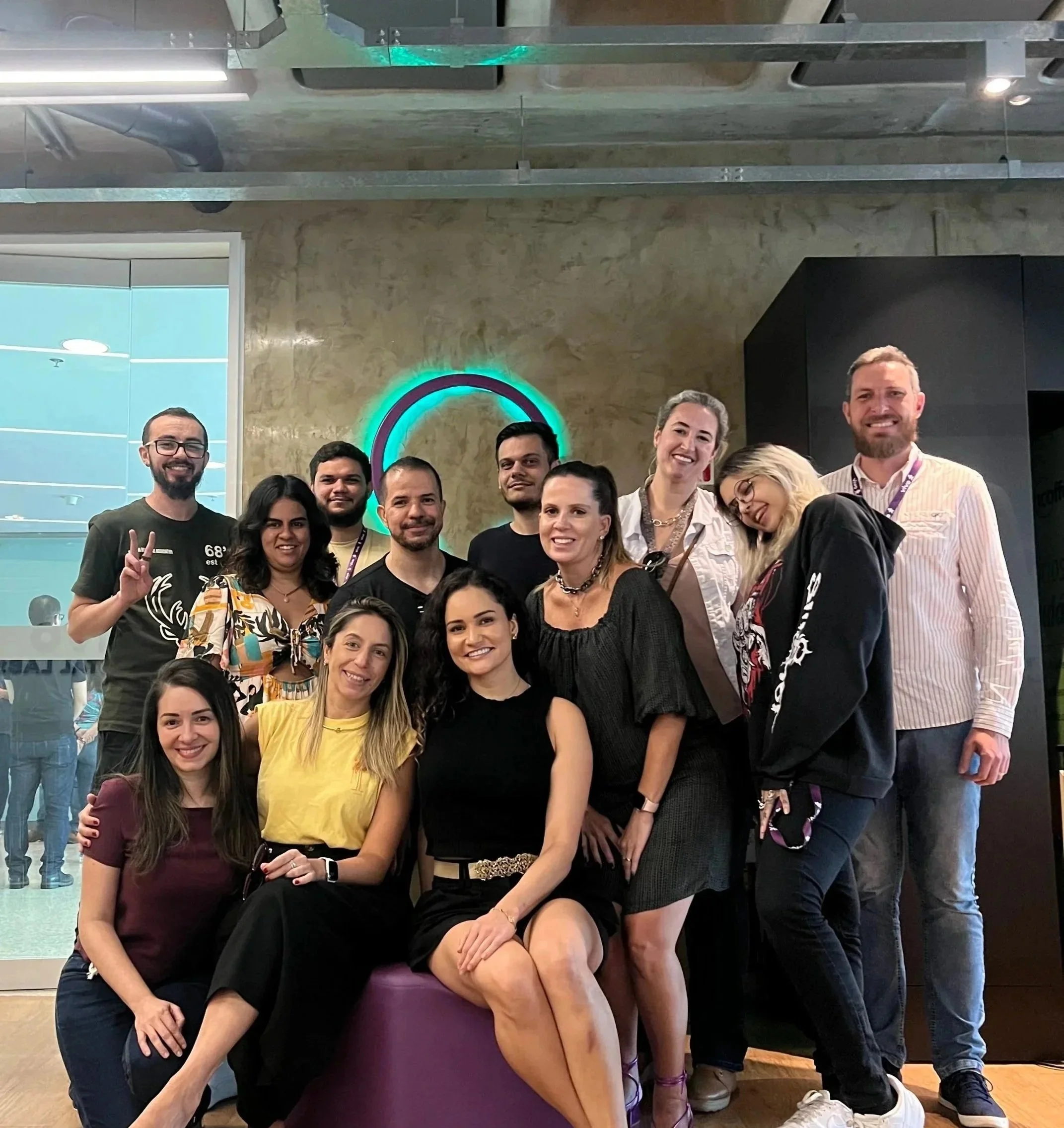 A group of eleven colleagues posing together and smiling in a modern office space, representing a product team.