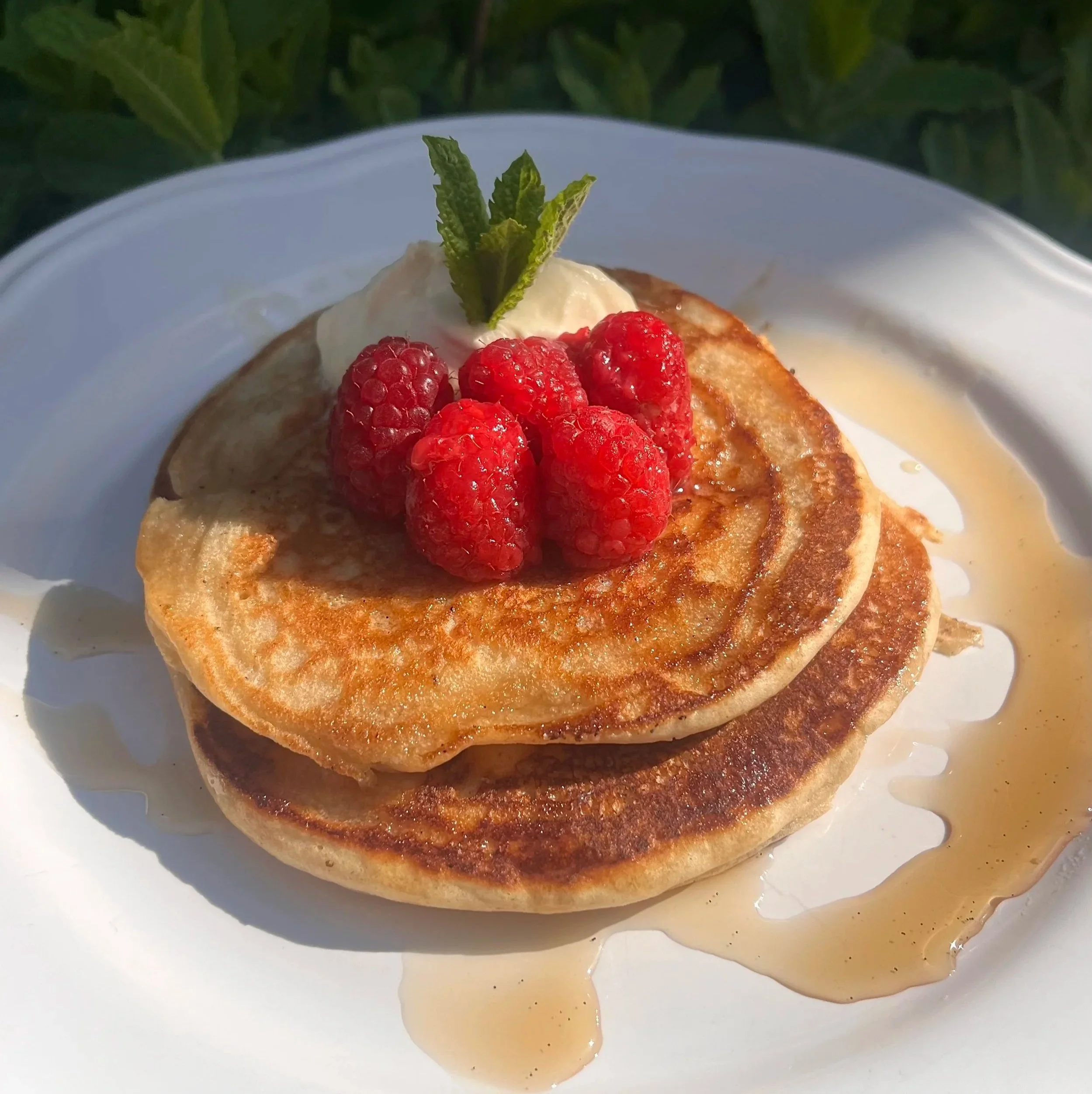 Gluten free protein pancake  vanilla bean syrup raspberries and softly whipped cream and mint garnish