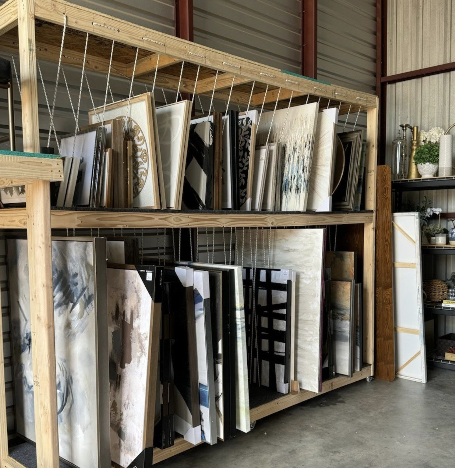 Wooden retail display shelf with various large tiles or slabs, including marble and stone patterns, stored upright in a warehouse or store.