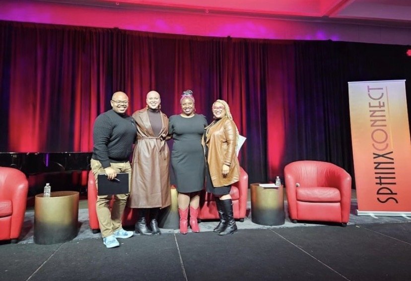 Four people standing on stage with a red curtain background, two red armchairs, and a banner that reads 'SPHINX CONNECT'.