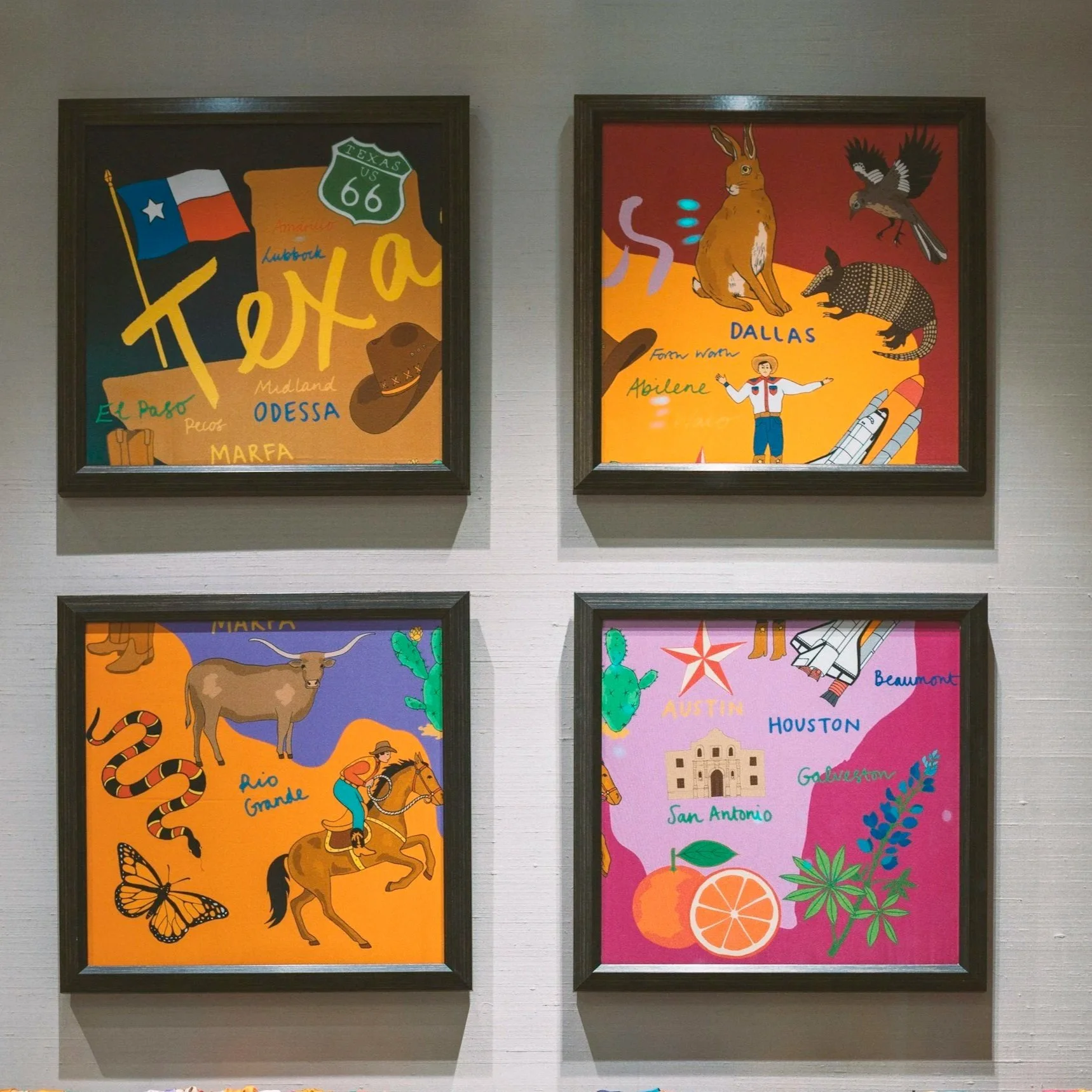 Two framed postcards, one depicting Texas symbols including a flag, cowboy hat, and the words 'El Paso,' 'Odessa,' 'Midland,' and 'Marfa'; the other showing animals like a rabbit, armadillo, and bird, with a person and landmarks, along with names of Texas cities like Dallas, Austin, Houston, San Antonio, and Galveston, and colorful illustrations of oranges and cacti.