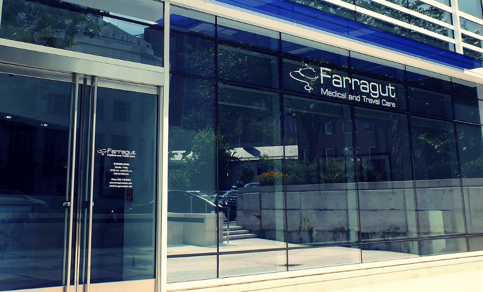 Exterior of a modern glass building with the sign 'Farragut Medical and Travel Care'.