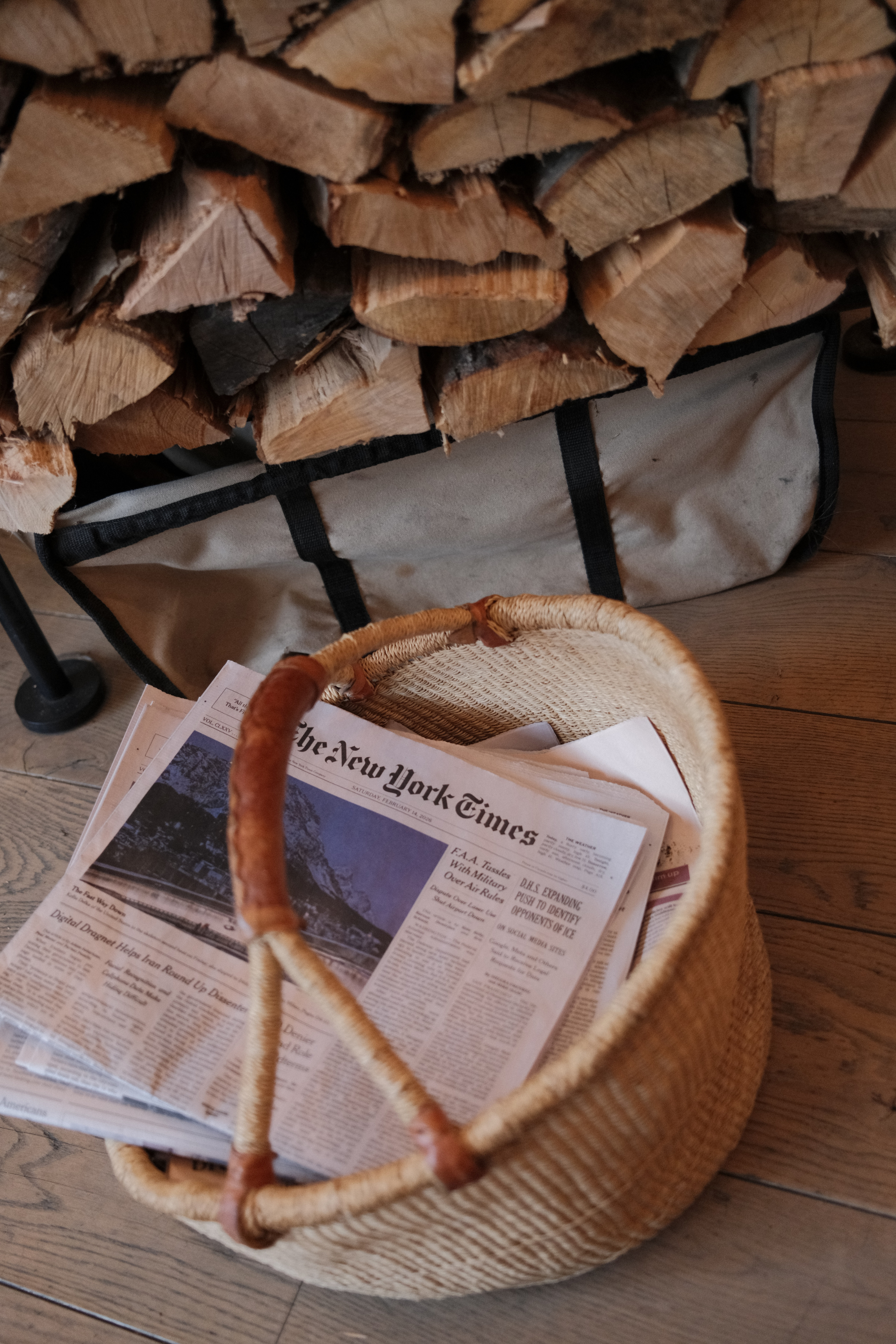 Basket with copies of The New York Times in front of a stack of firewood
