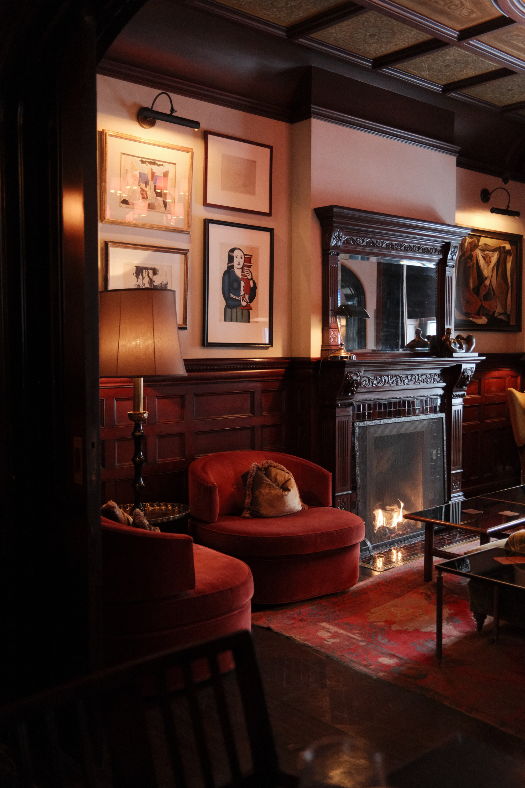 Two red chairs, a fireplace, and gallery wall