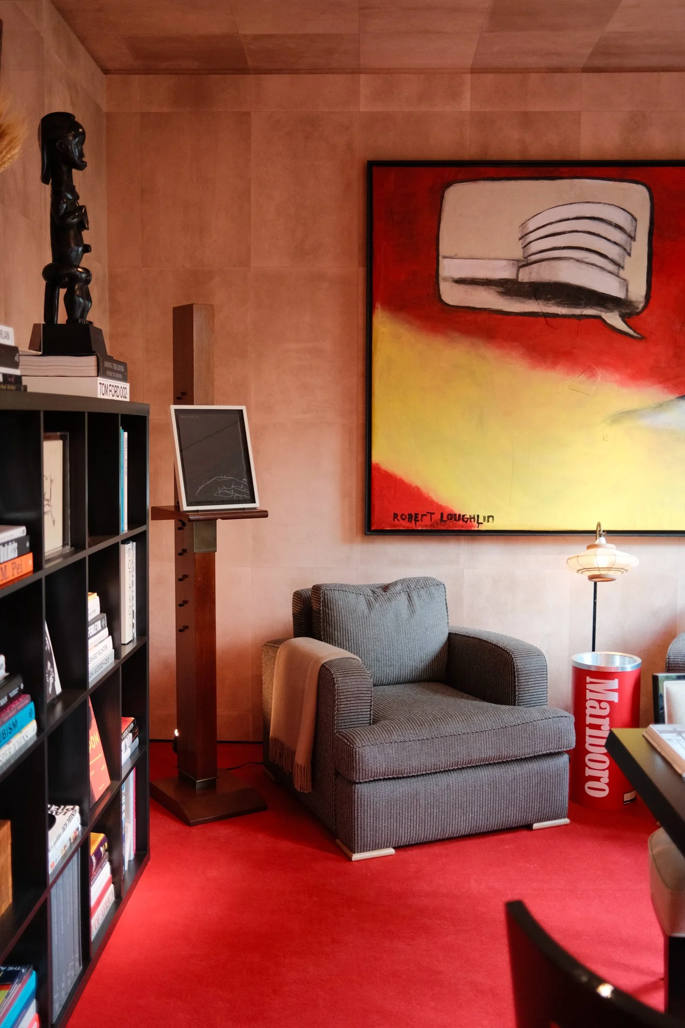 Room with red carpet and blue armchair under large art piece
