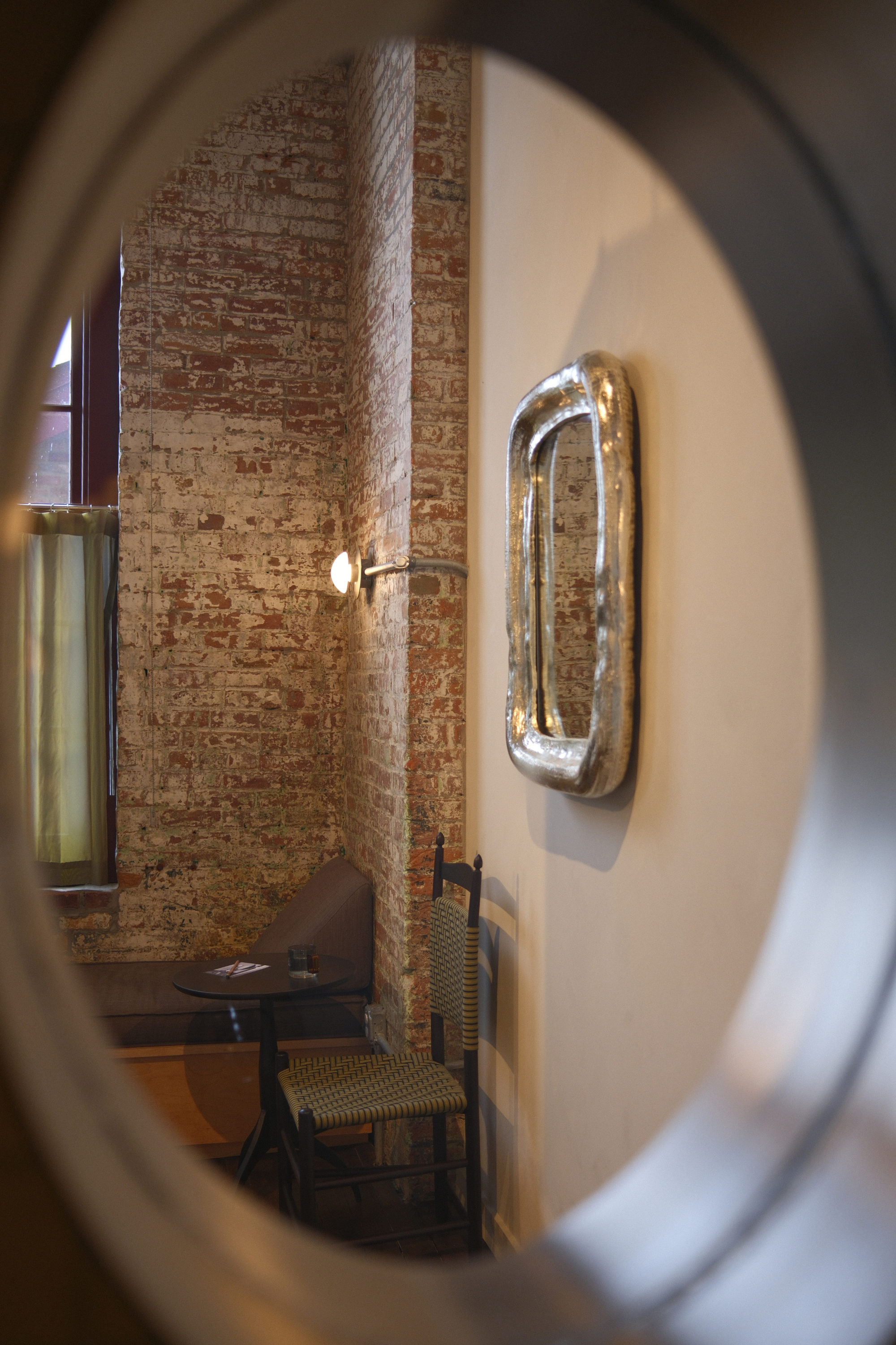 Window looking into guest room corner with mirror and chair