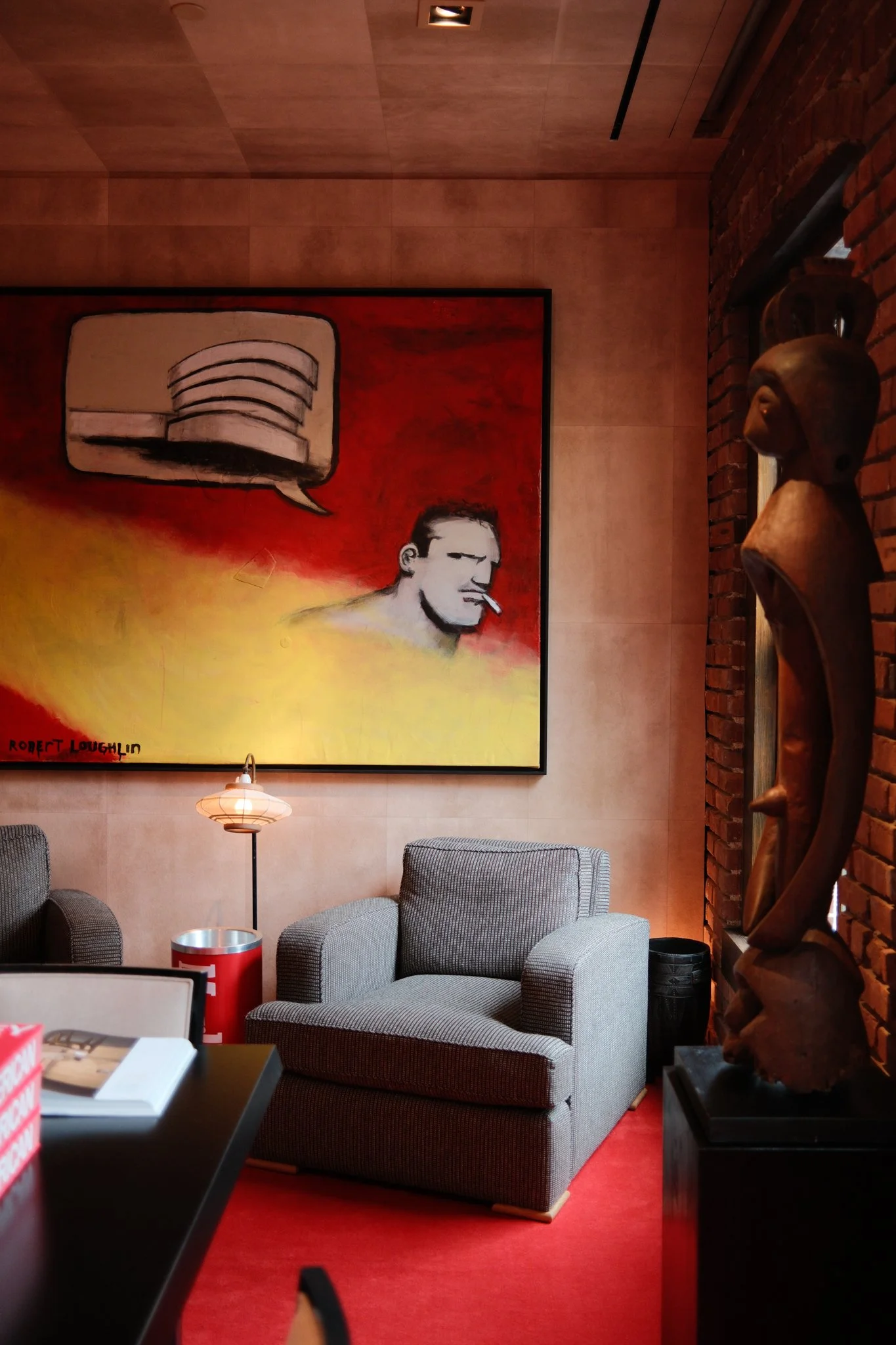 Room with red carpet, a blue chair, and a large painting on the wall