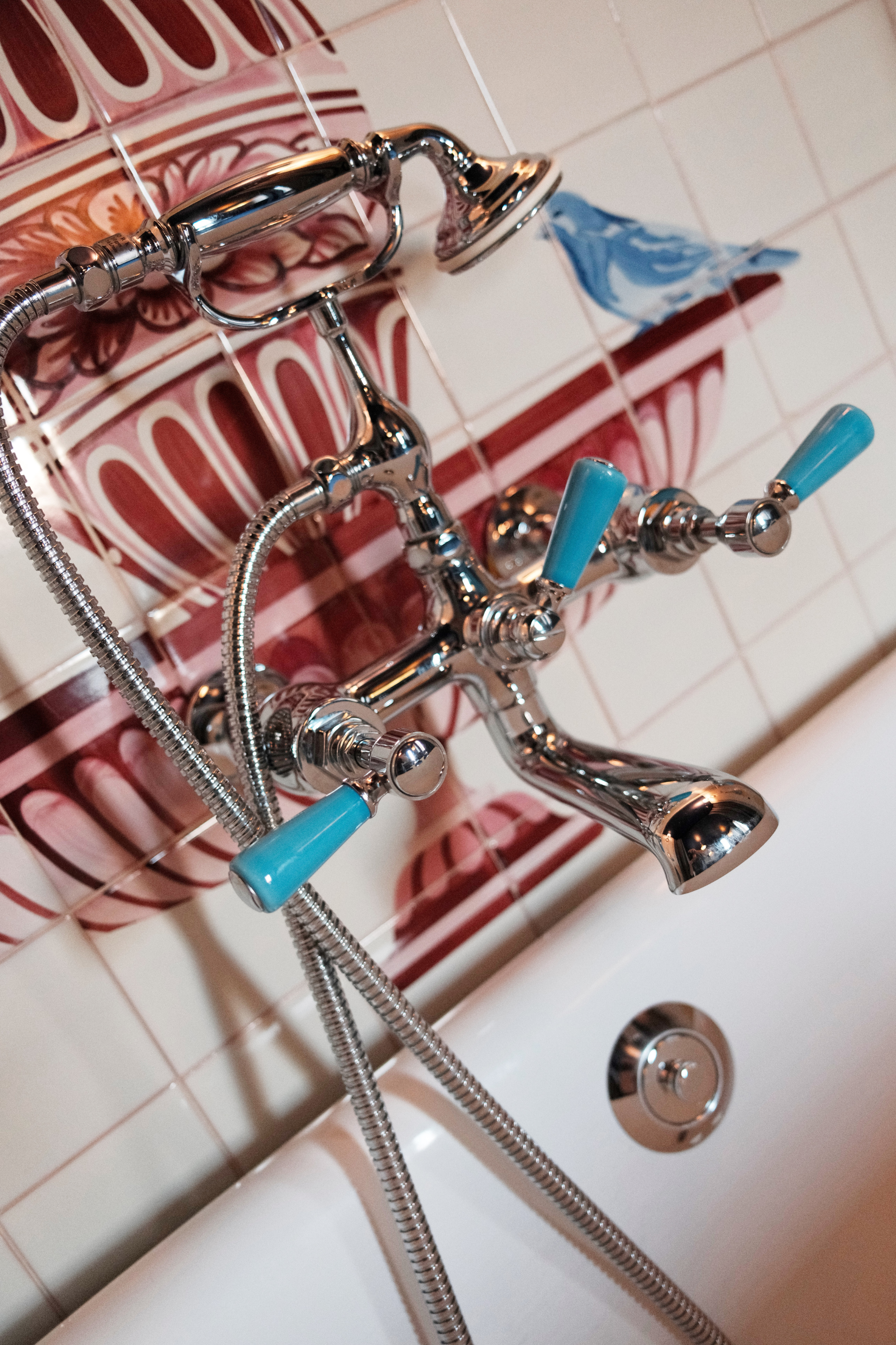 Silver and teal bathtub hardware with painted tile