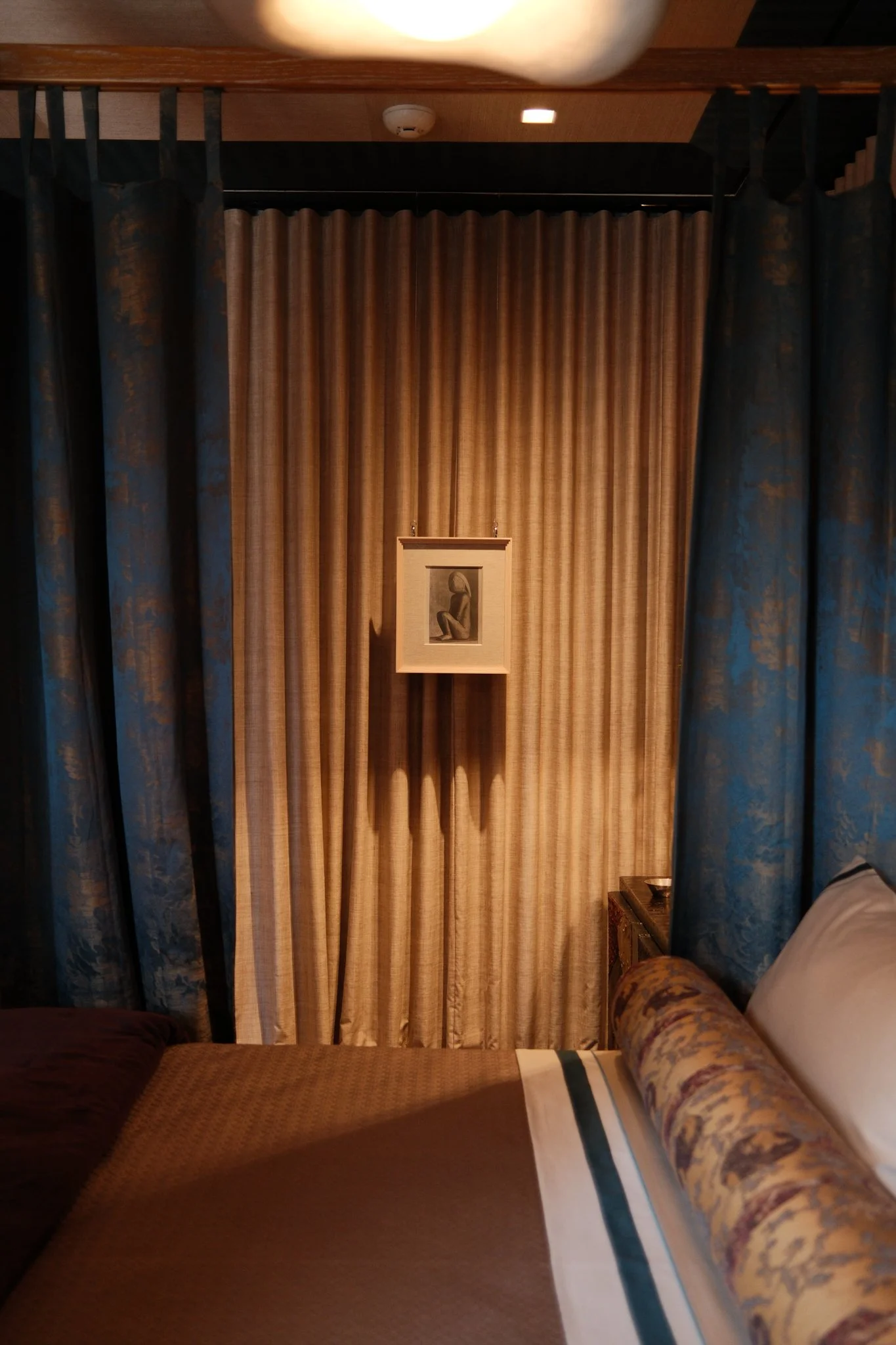 view across canopy bed to hanging art and drapes