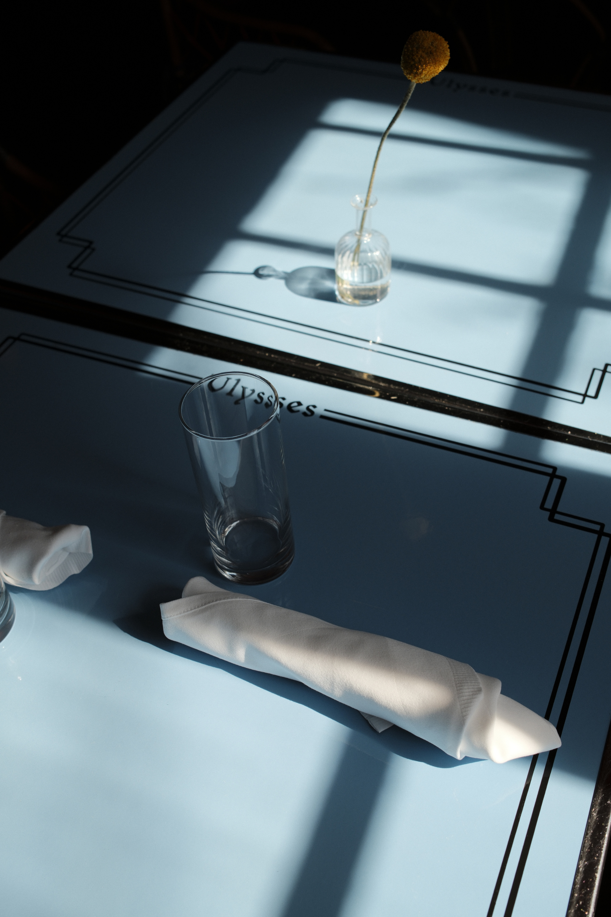Ash-Bar table with napkins, glassware, and a bud vase with yellow flower